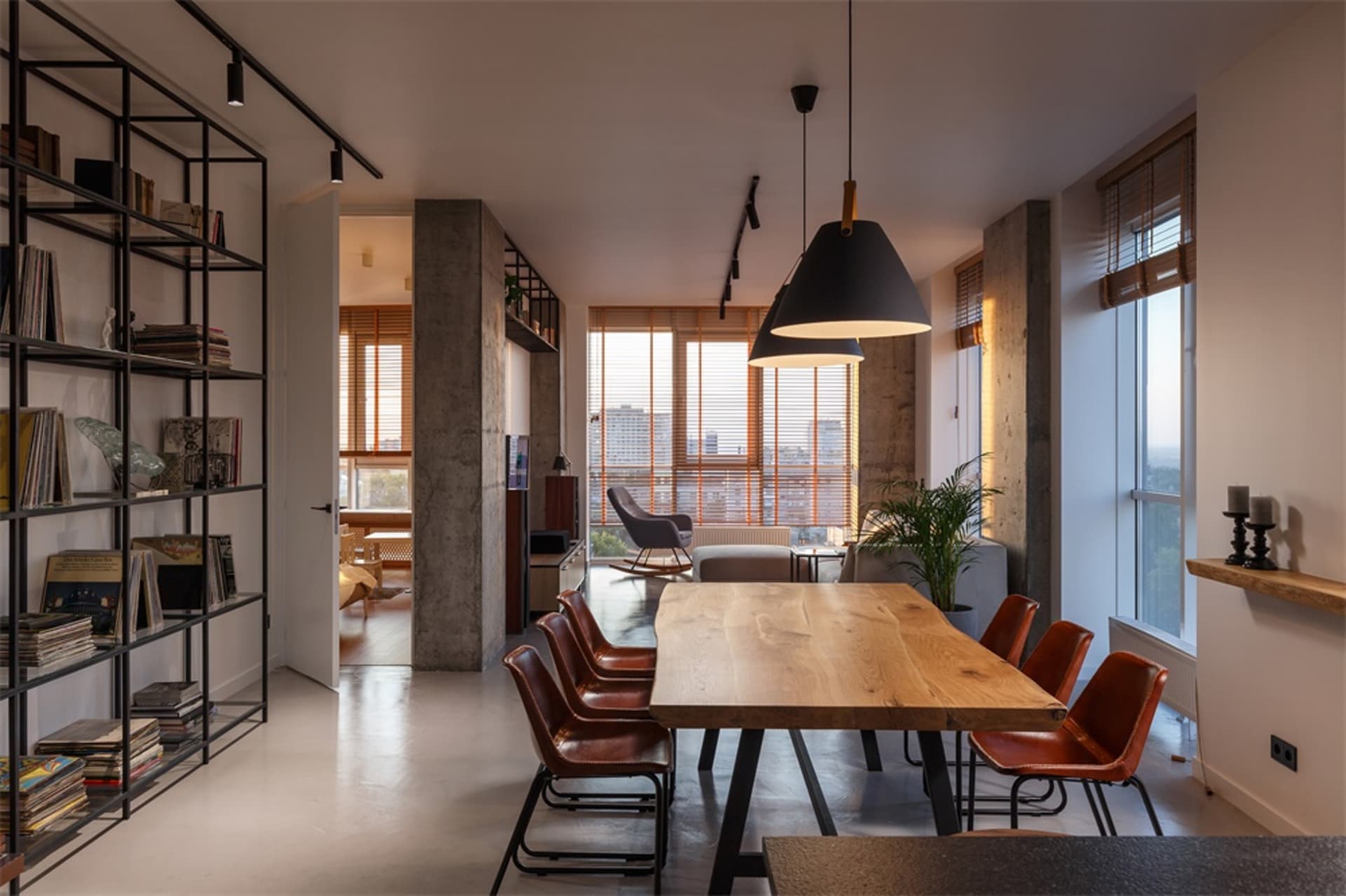Dining room with city view featuring a wooden table and chairs with a concrete pillar.