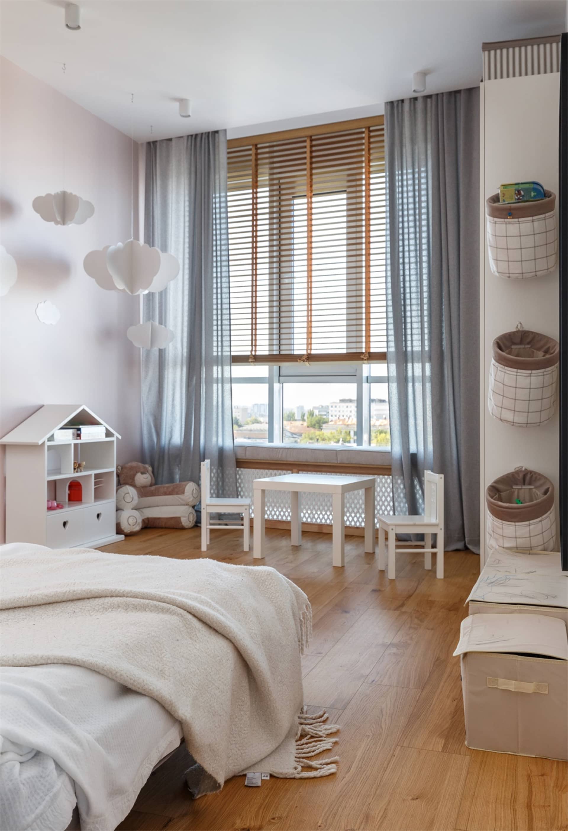Minimalist bedroom with white furniture, grey curtains, wooden flooring, and decorative clouds on the wall.