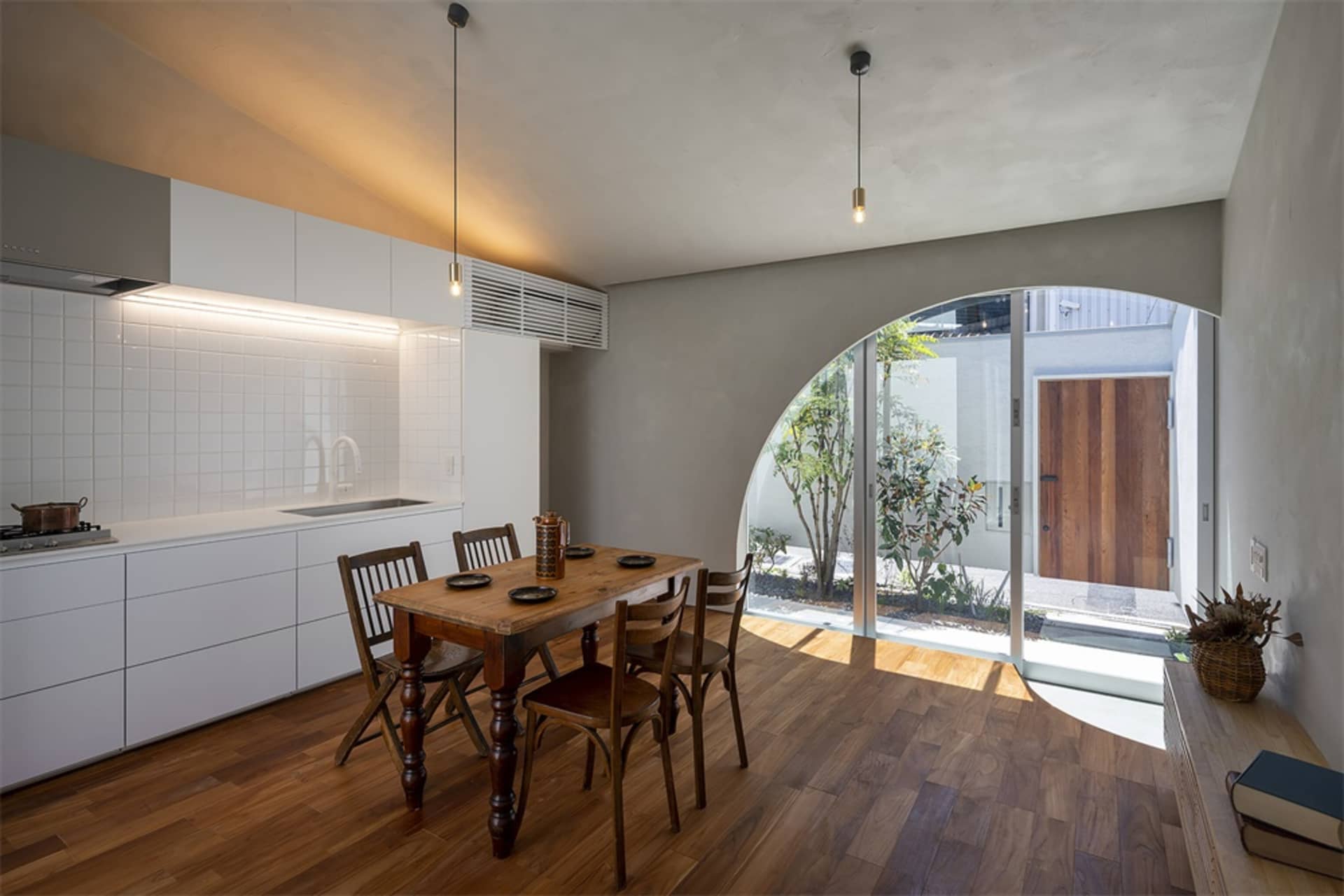 A minimalist residential kitchen with wooden elements and a view of the courtyard.