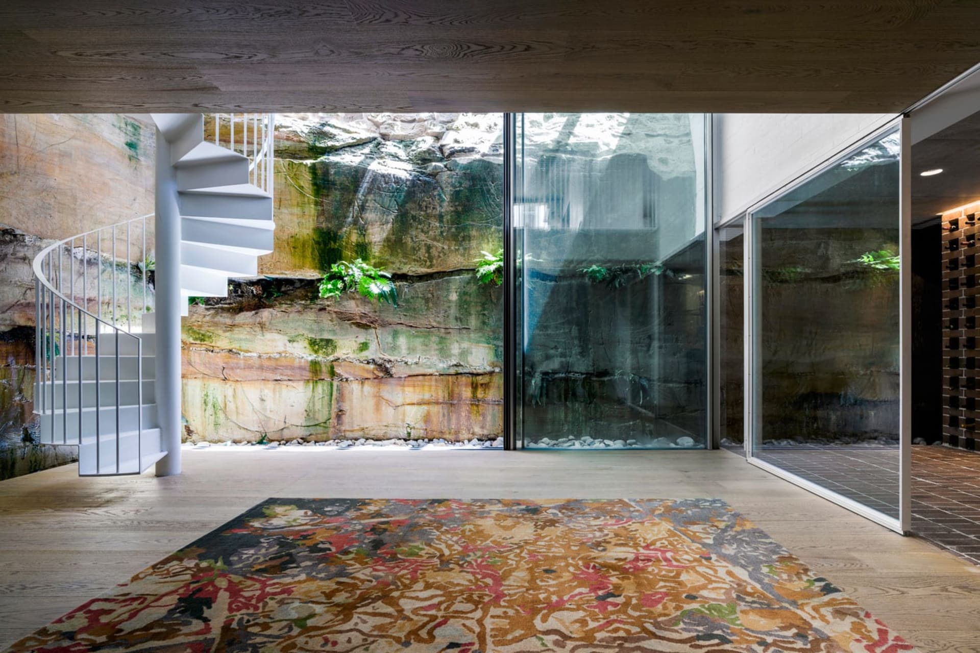 A modern interior space with a wooden floor and natural light streaming through glass walls.