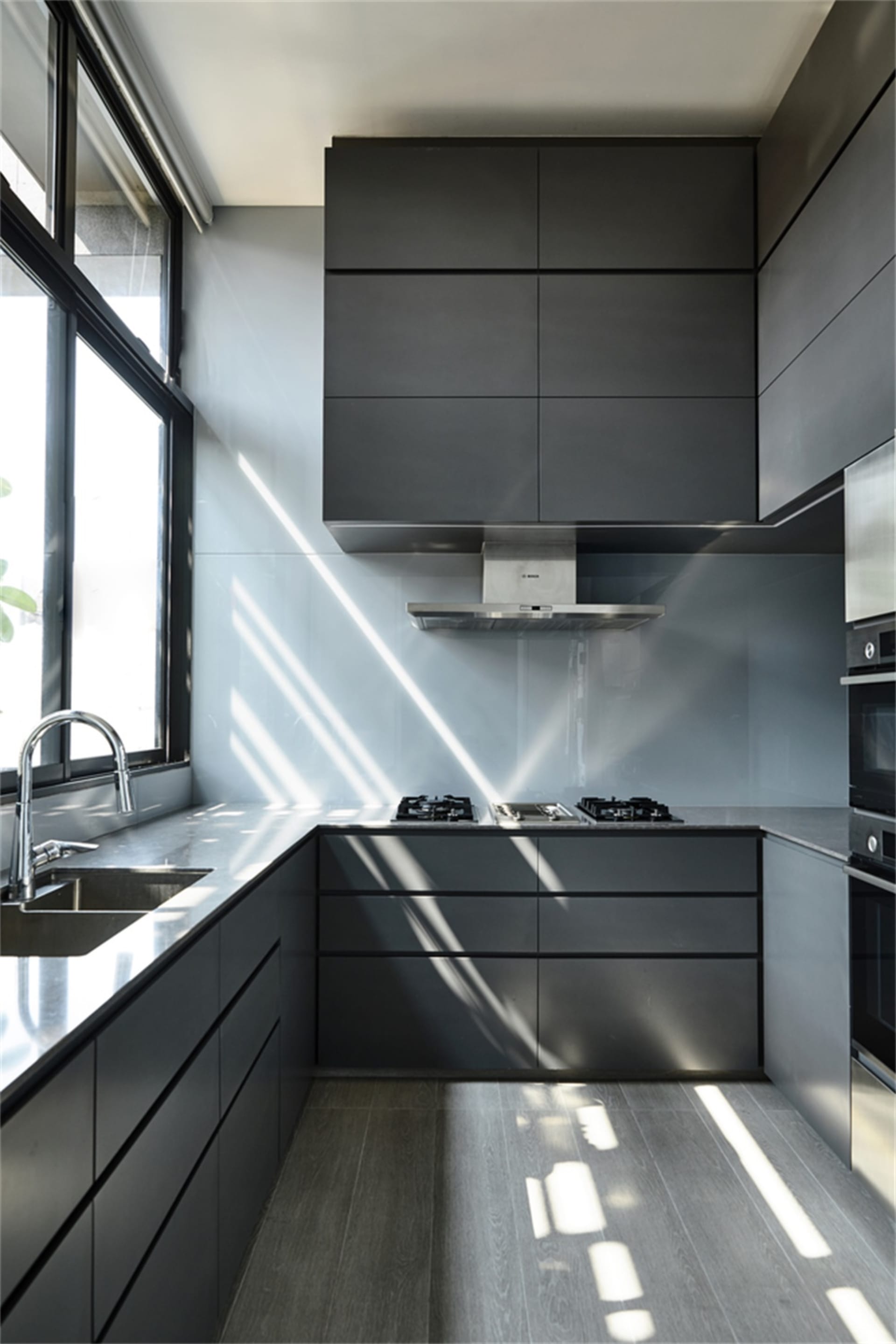 Modern kitchen featuring sleek black cabinets and glass countertops.