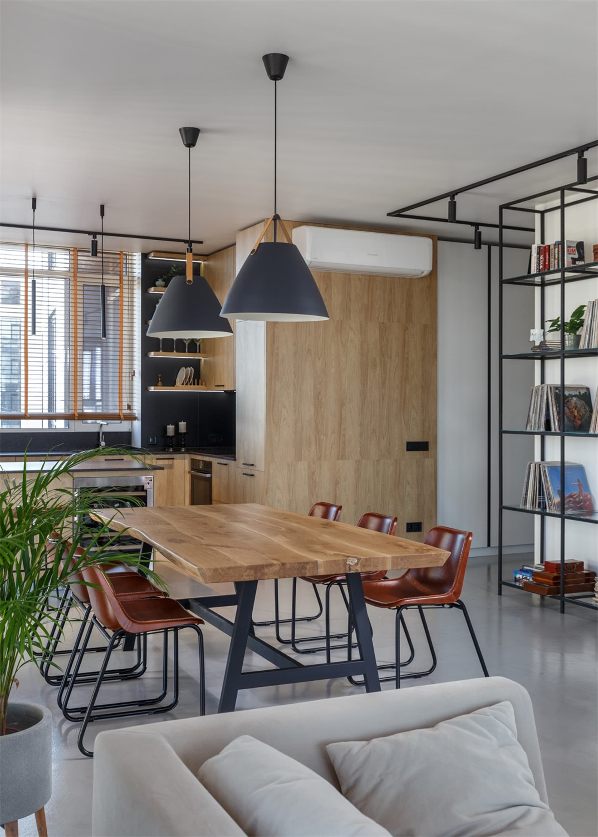 Modern dining room with wooden furniture, black pendant lights, and a mix of leather and metal chairs.