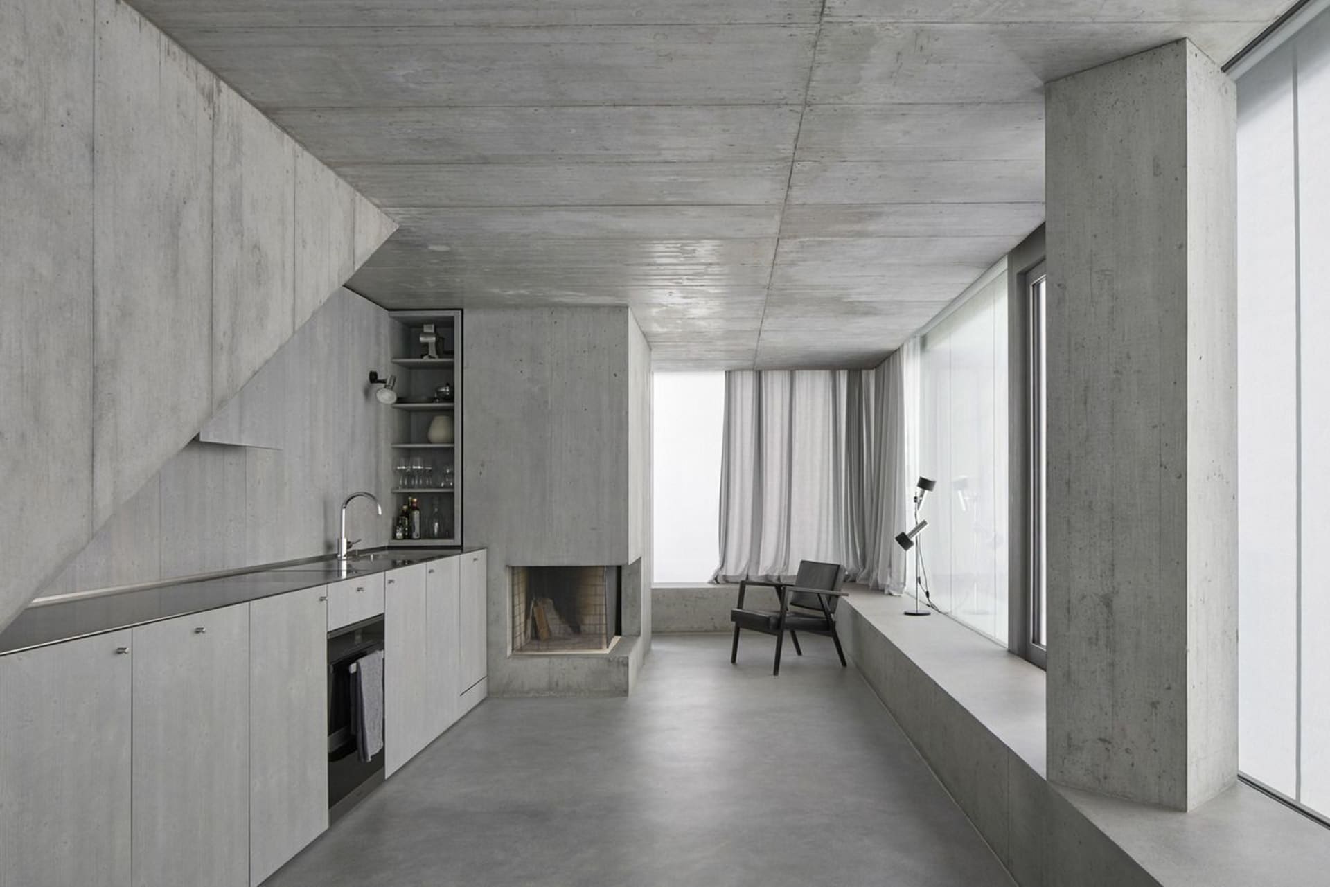 A modern, minimalist kitchen with concrete countertops and walls.