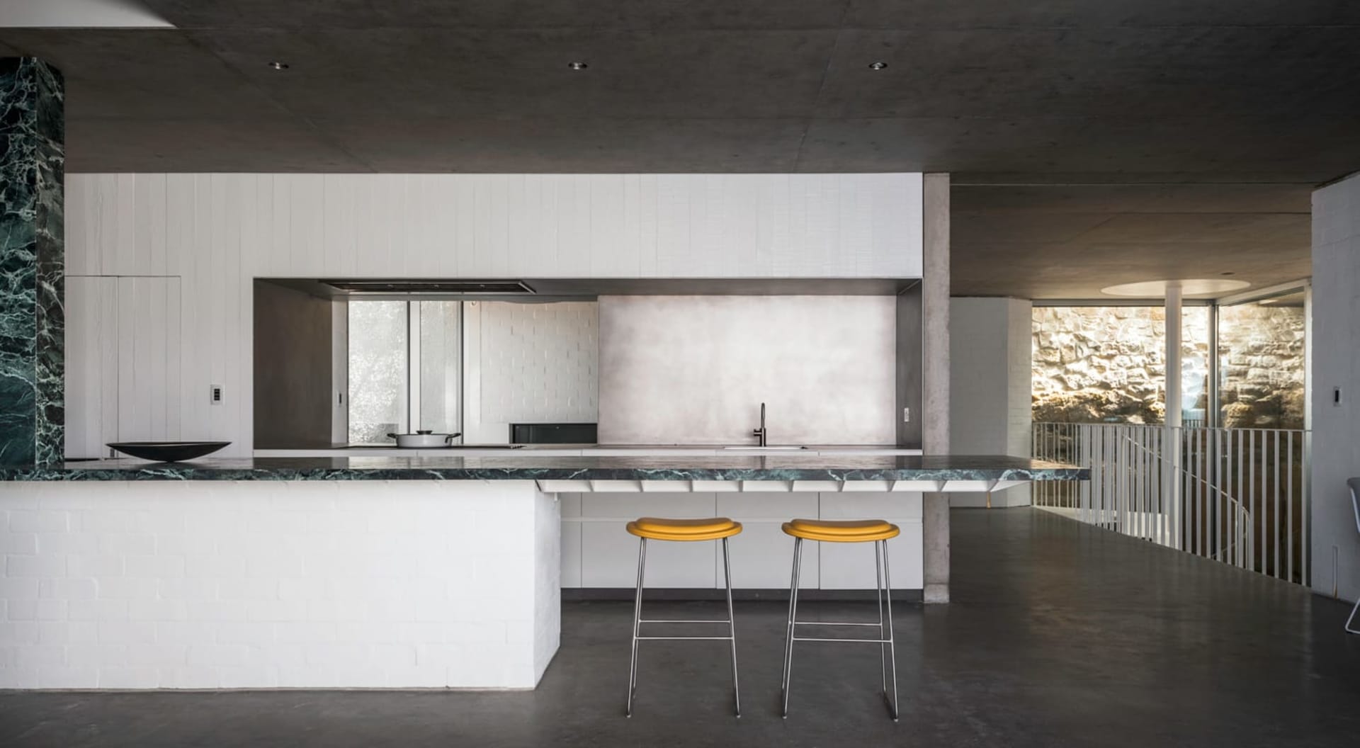 Modern kitchen featuring concrete countertops and white brick walls.