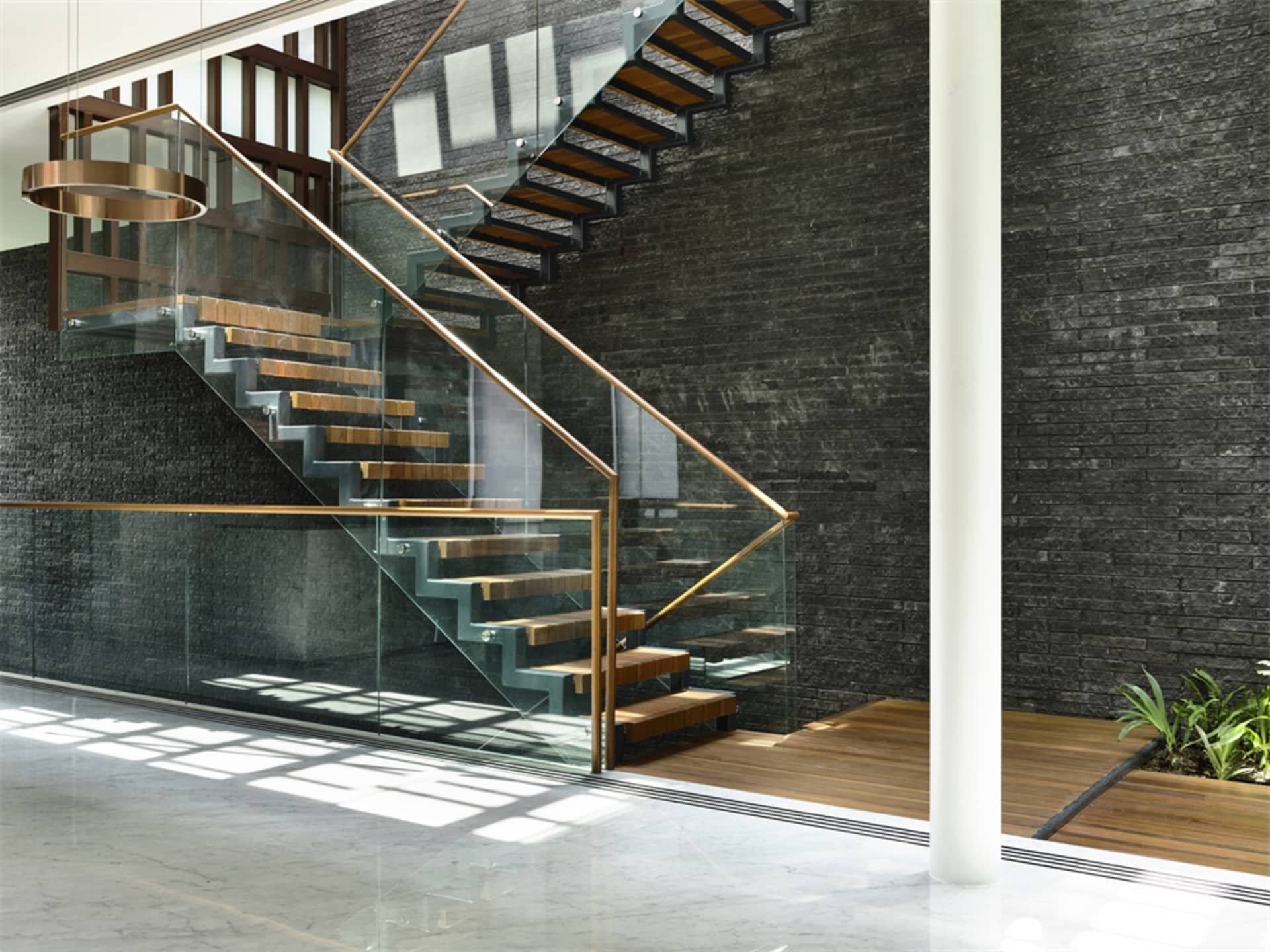 Modern staircase with glass railings and metallic steps.