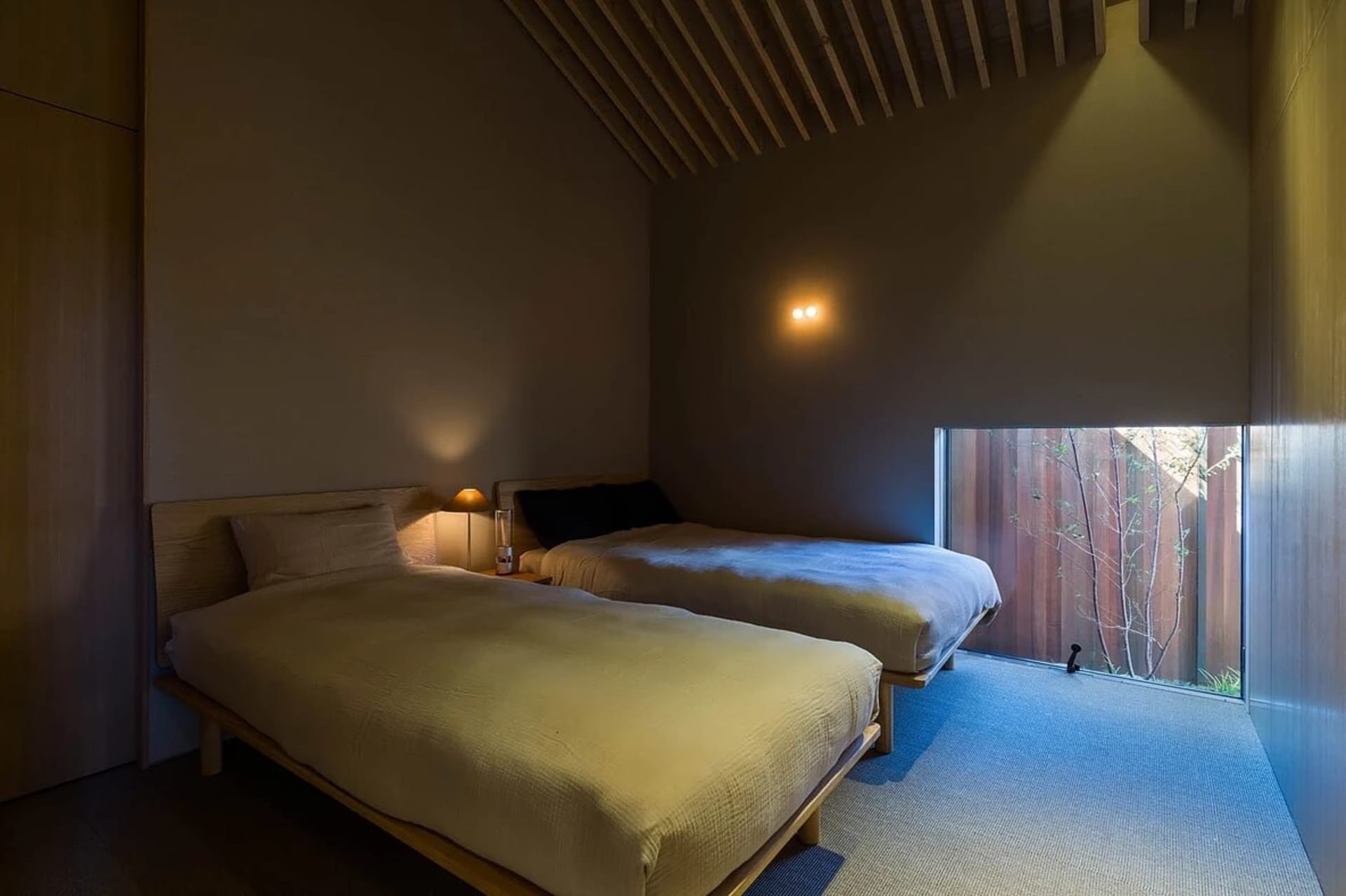 A minimalist bedroom with wooden furniture and light-colored bedding.