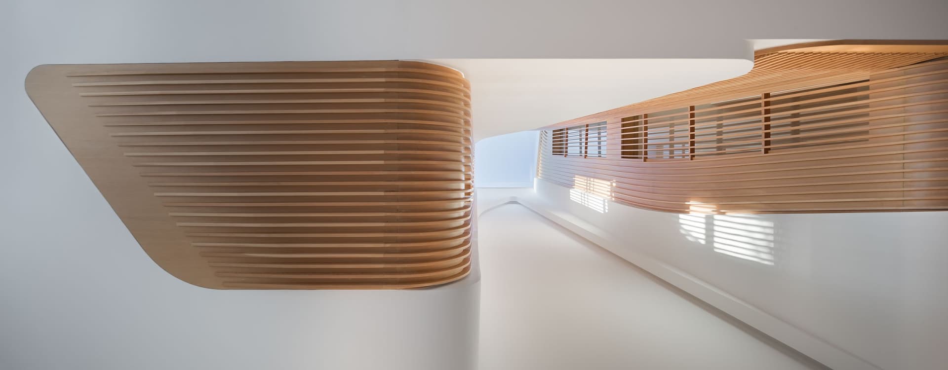 A modern interior corridor with wooden paneling and light streaming in from windows.