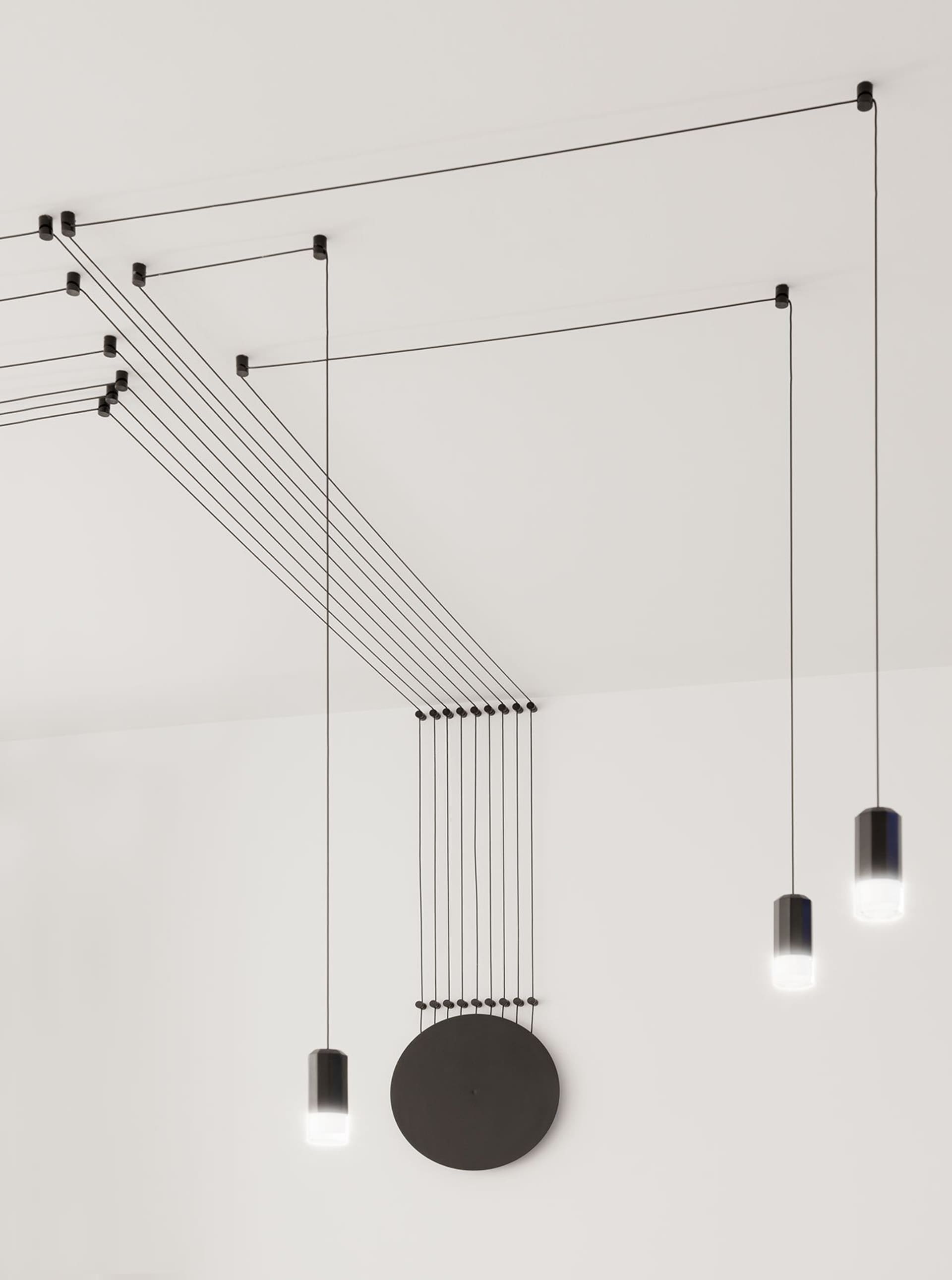 A modern lighting installation featuring a black cable structure and cylindrical light fixtures.