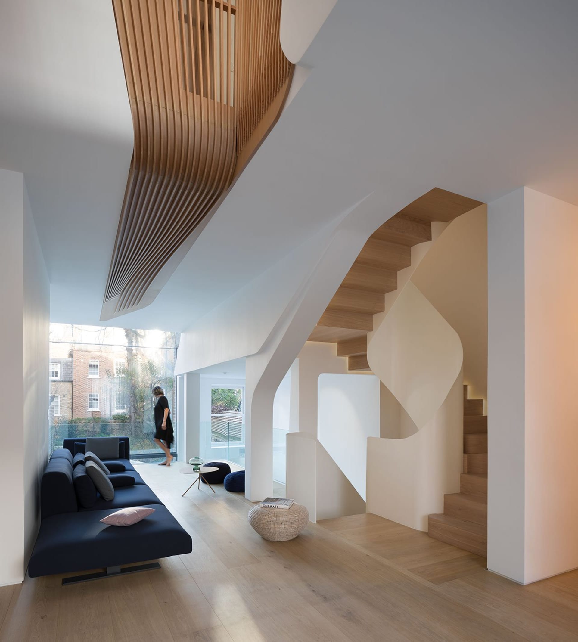 A modern residential interior featuring concrete stairs, wooden elements, and glass windows.