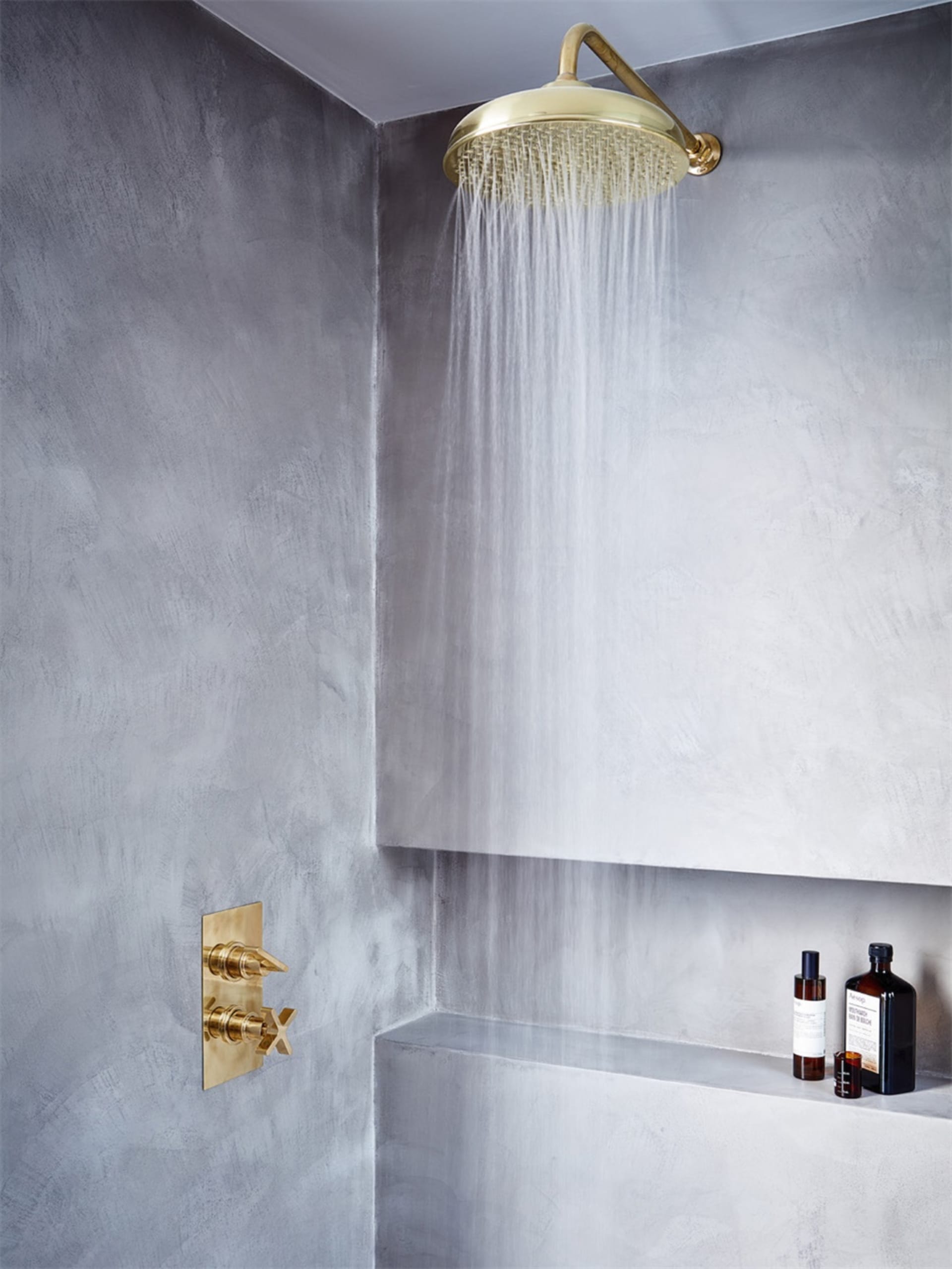 Modern bathroom featuring a shower with a concrete wall and brass fixtures.