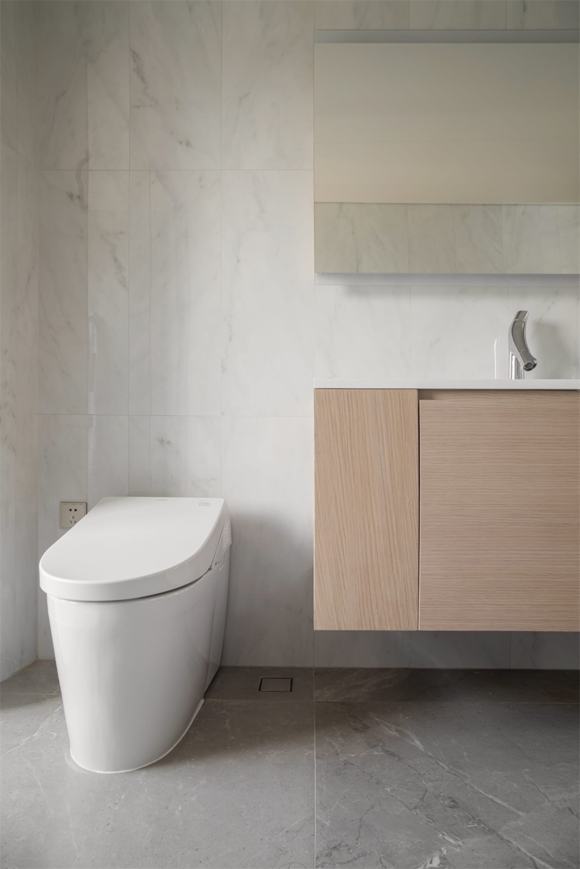 Modern bathroom with minimalist marble design and white toilet.