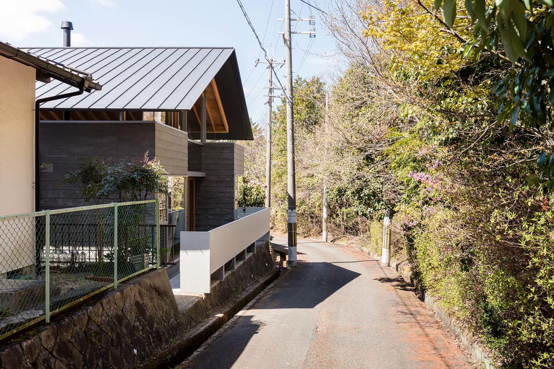A modern minimalist home with a dark metal roof and concrete walls.