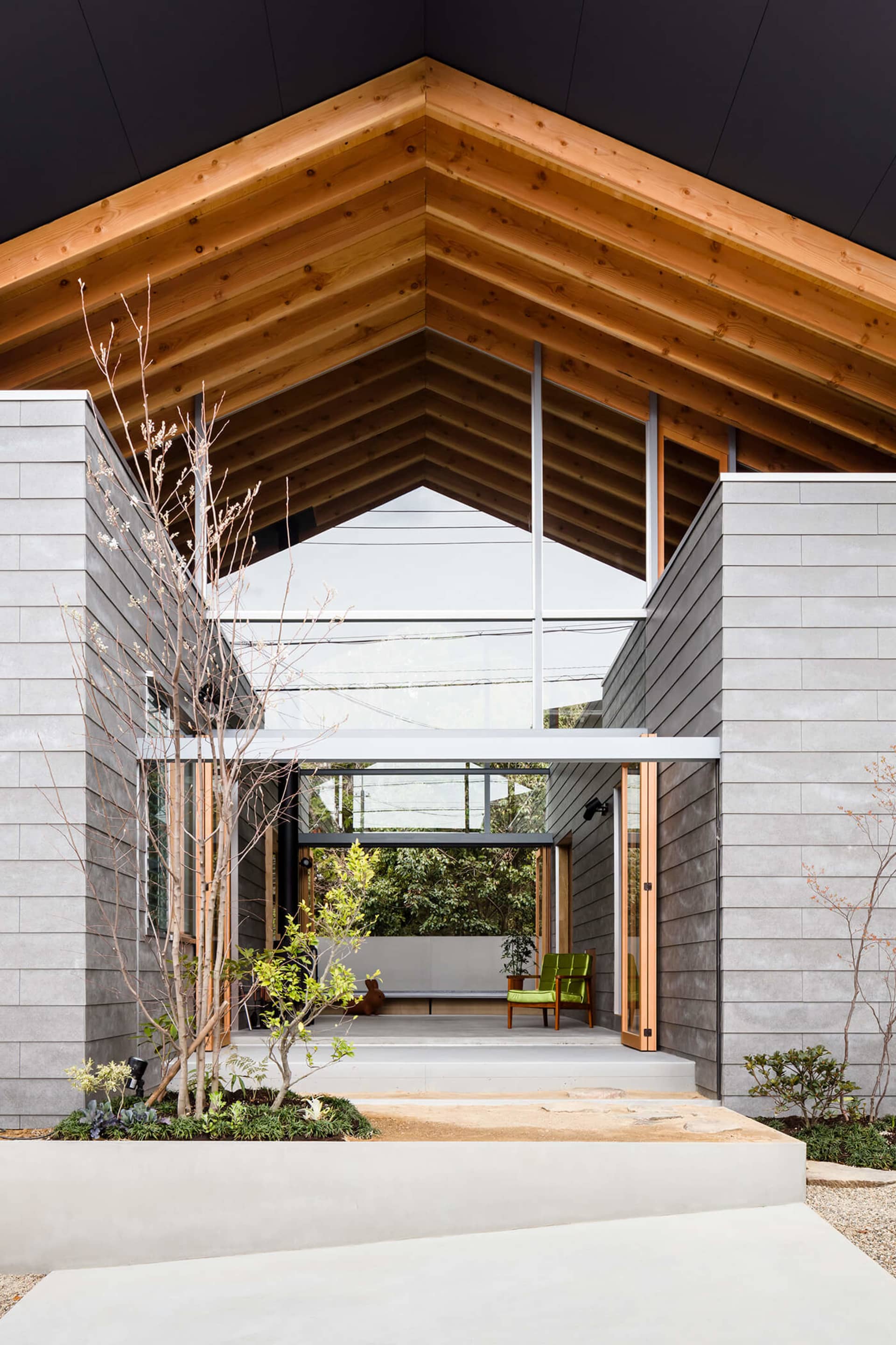 Modern minimalist residential entry veranda with green armchair and white bench.