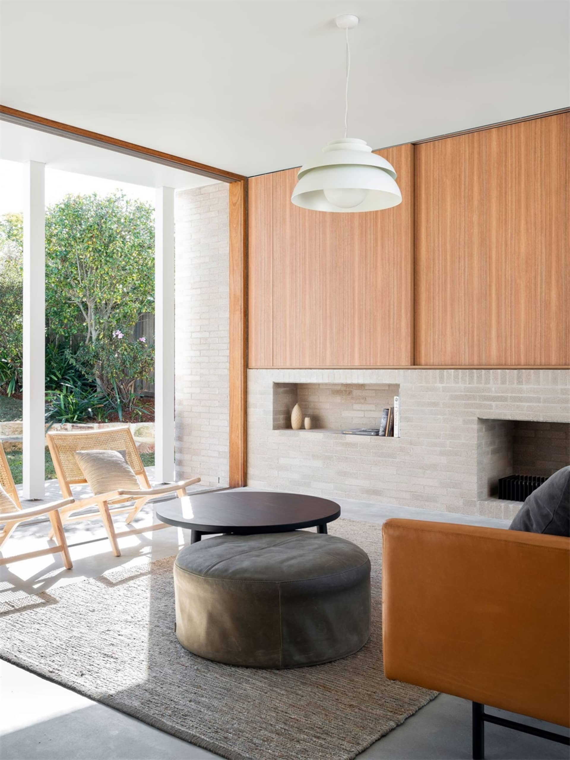 A minimalist living room featuring wooden shelves, a round coffee table, and a leather sofa.