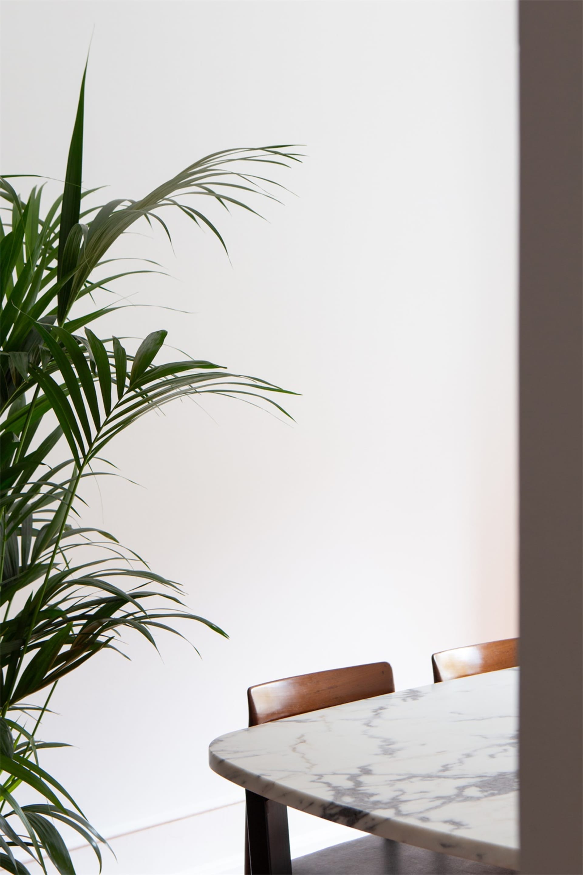A minimalist dining room featuring a marble table and wooden chairs.