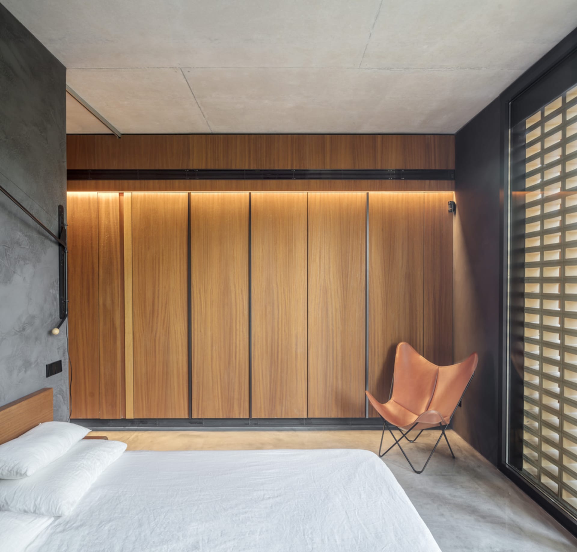 A modern bedroom featuring wooden walls and a butterfly chair.