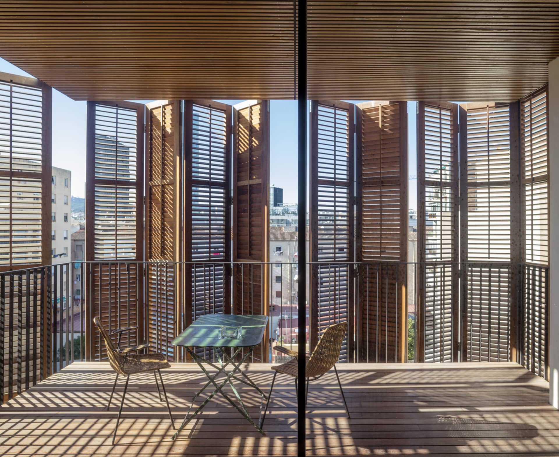 Modern balcony interior design with wooden shutters and metal railings.