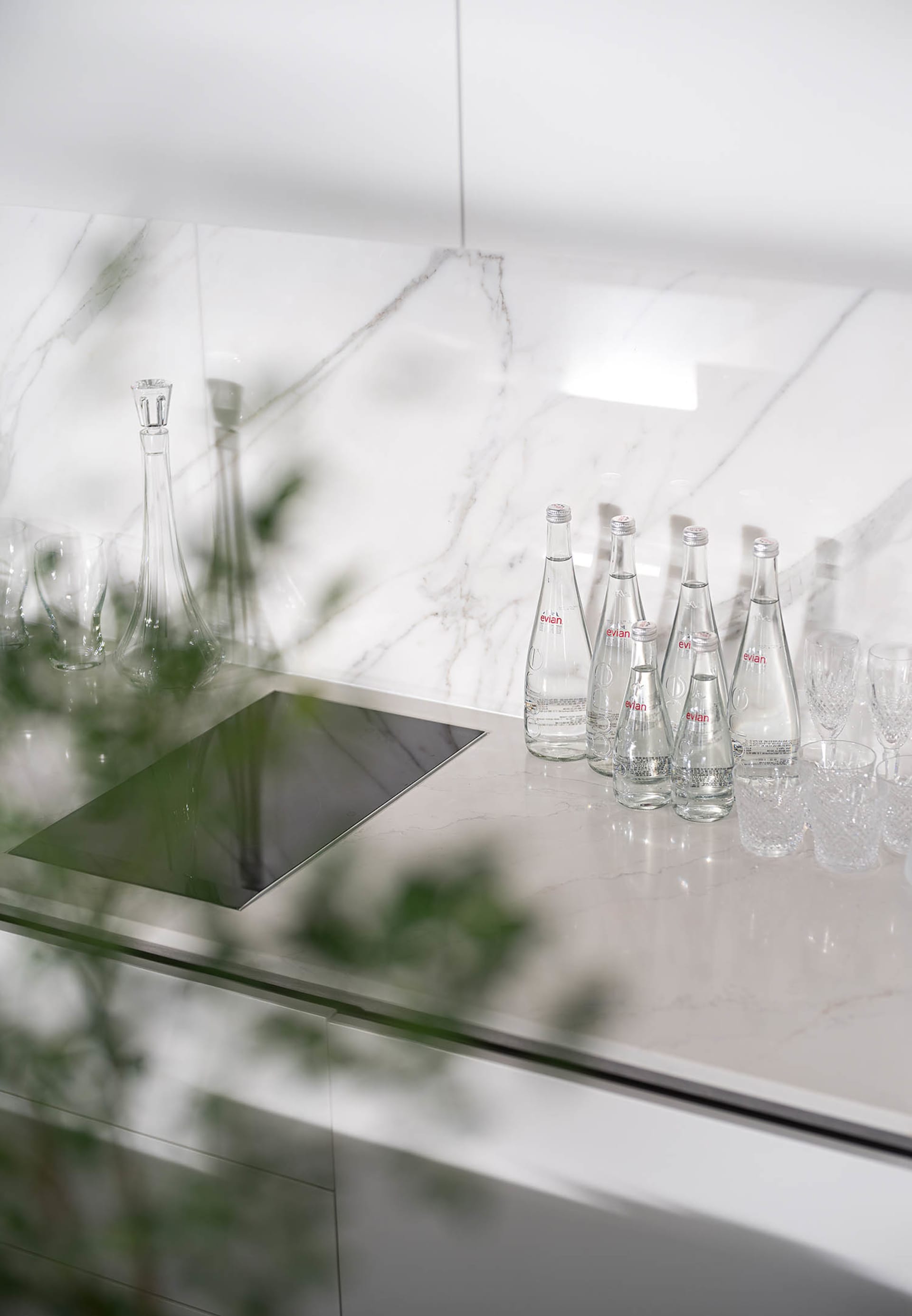 A minimalist residential kitchen featuring glass and marble materials.