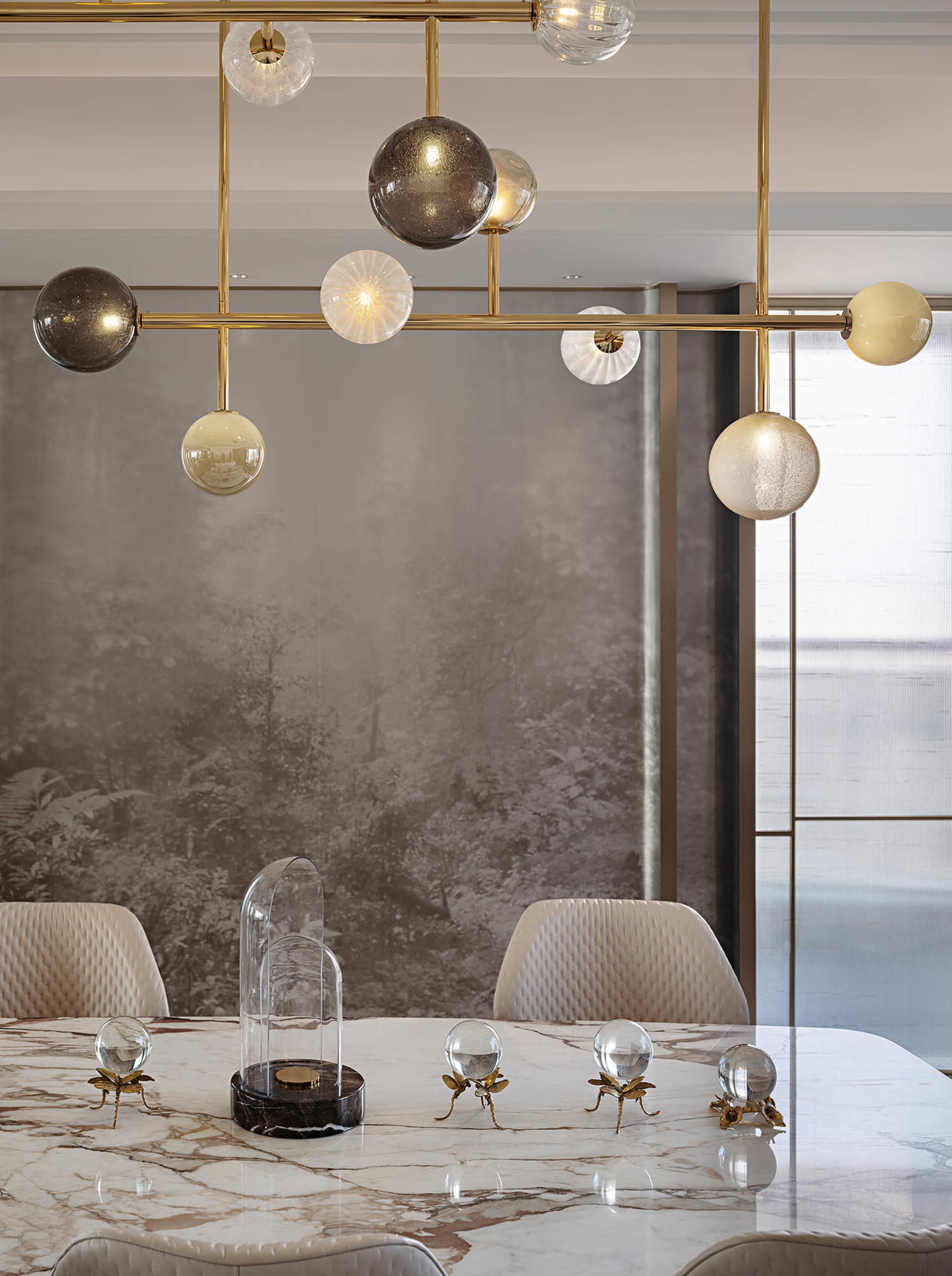 Modern dining room featuring marble table, glass light fixtures, and brass accents.