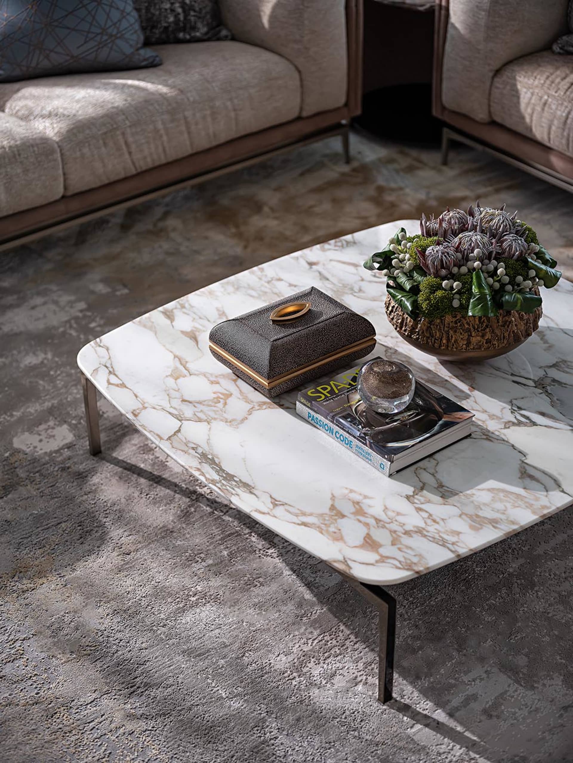 Modern living room with a marble coffee table, a book, and a flower arrangement.