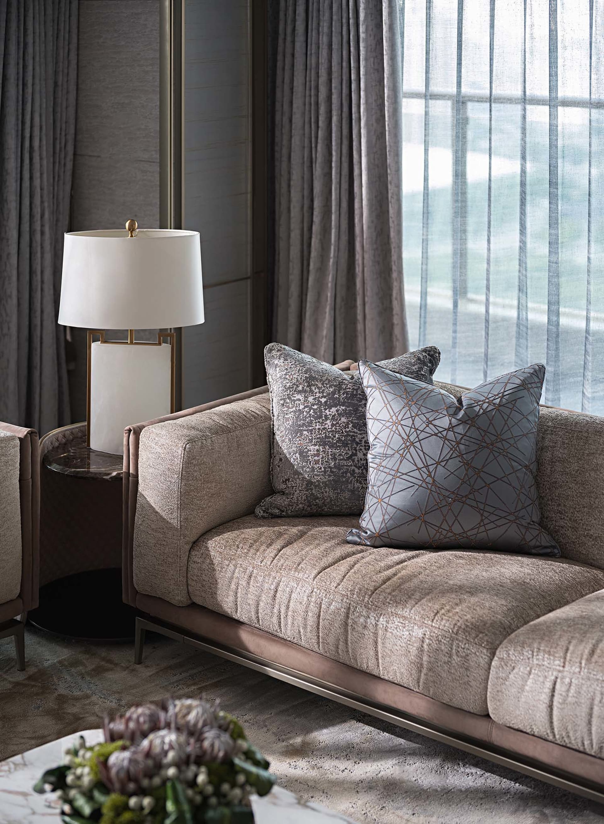 A modern living room featuring a plush, taupe-colored sofa adorned with geometric-patterned throw pillows, accompanied by a f