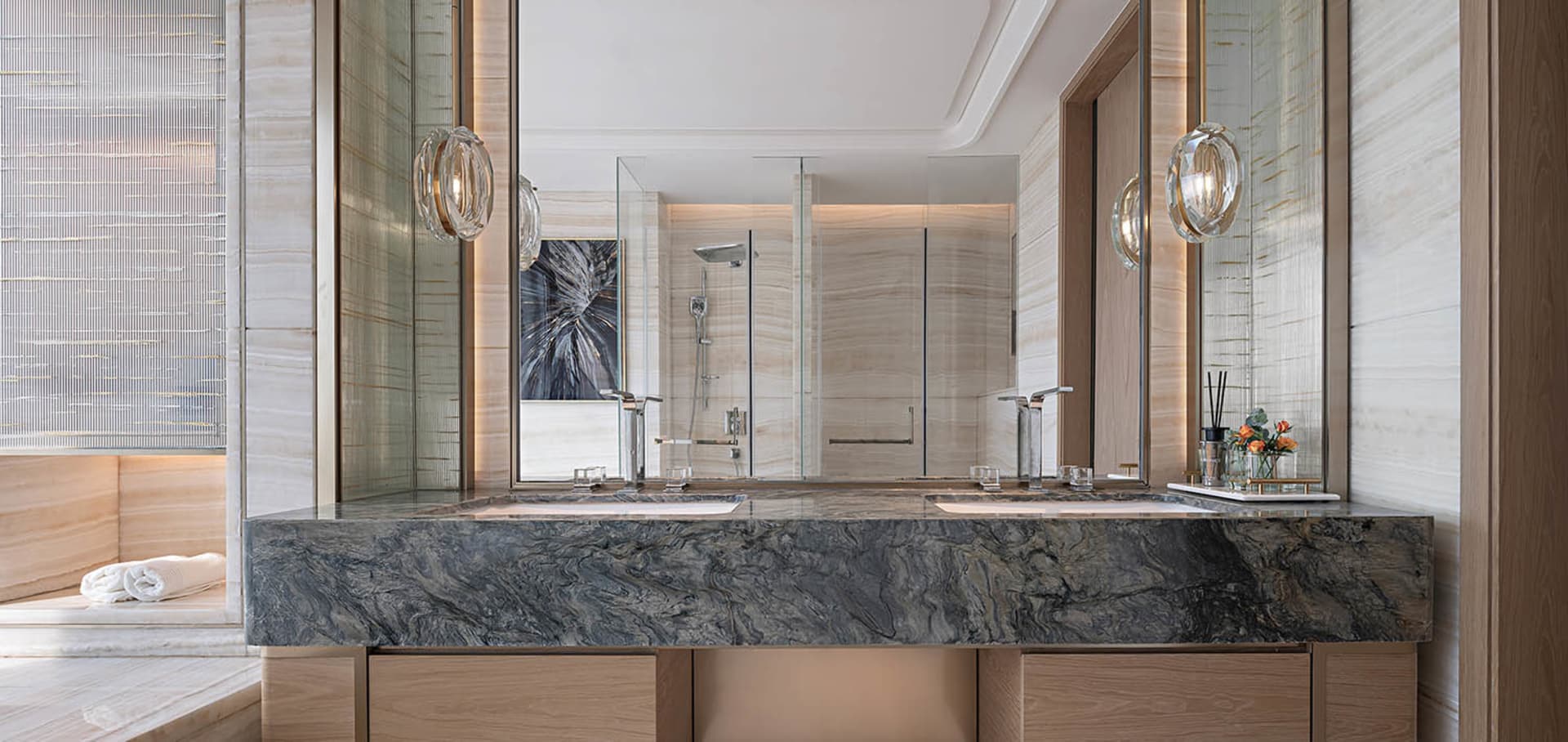 Modern bathroom featuring marble countertops, wooden cabinets, and a glass walk-in shower.