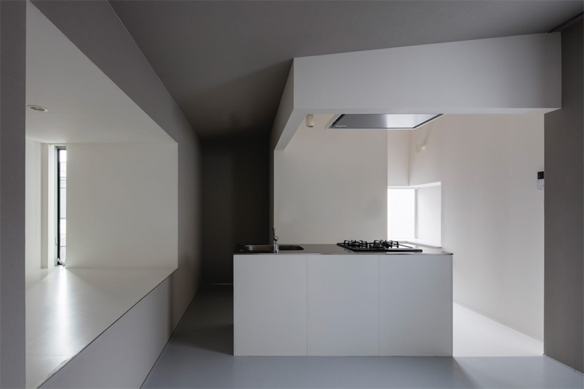 A minimalist residential kitchen featuring concrete and white materials.