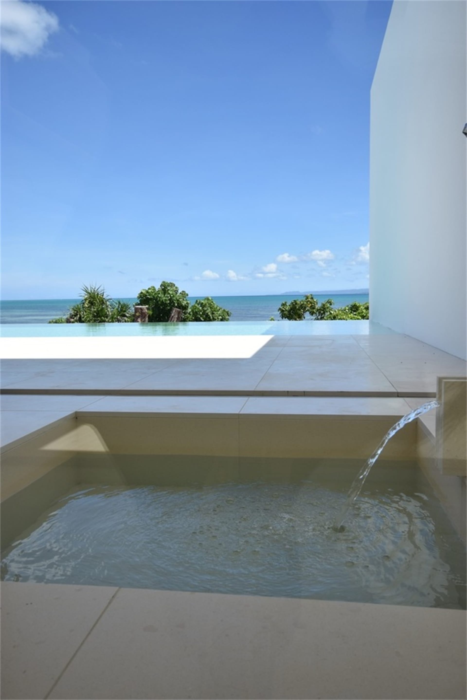 Modern vacation home with a glass infinity pool overlooking the ocean.