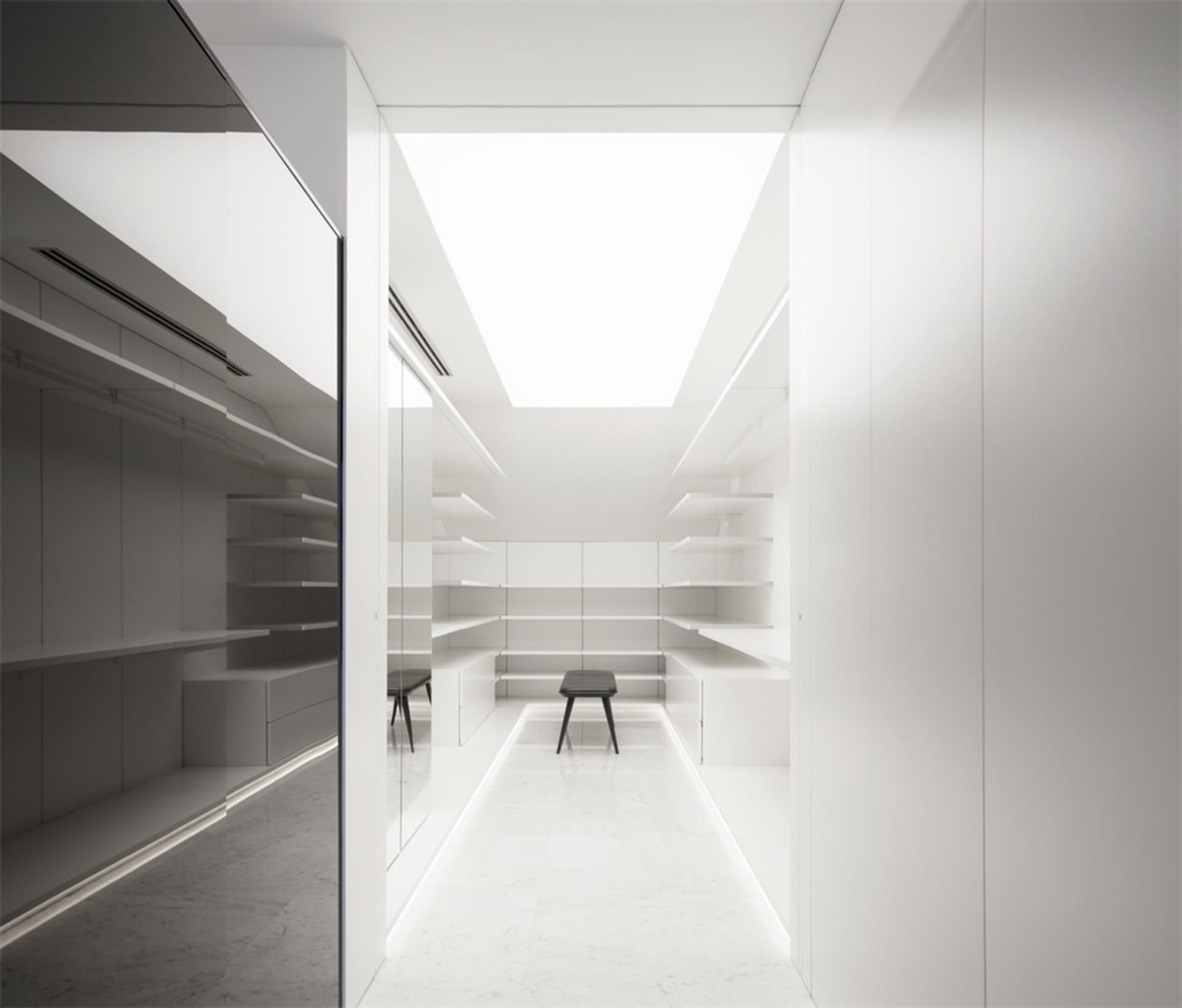 A minimalist white closet with clear glass sliding doors and shelves.