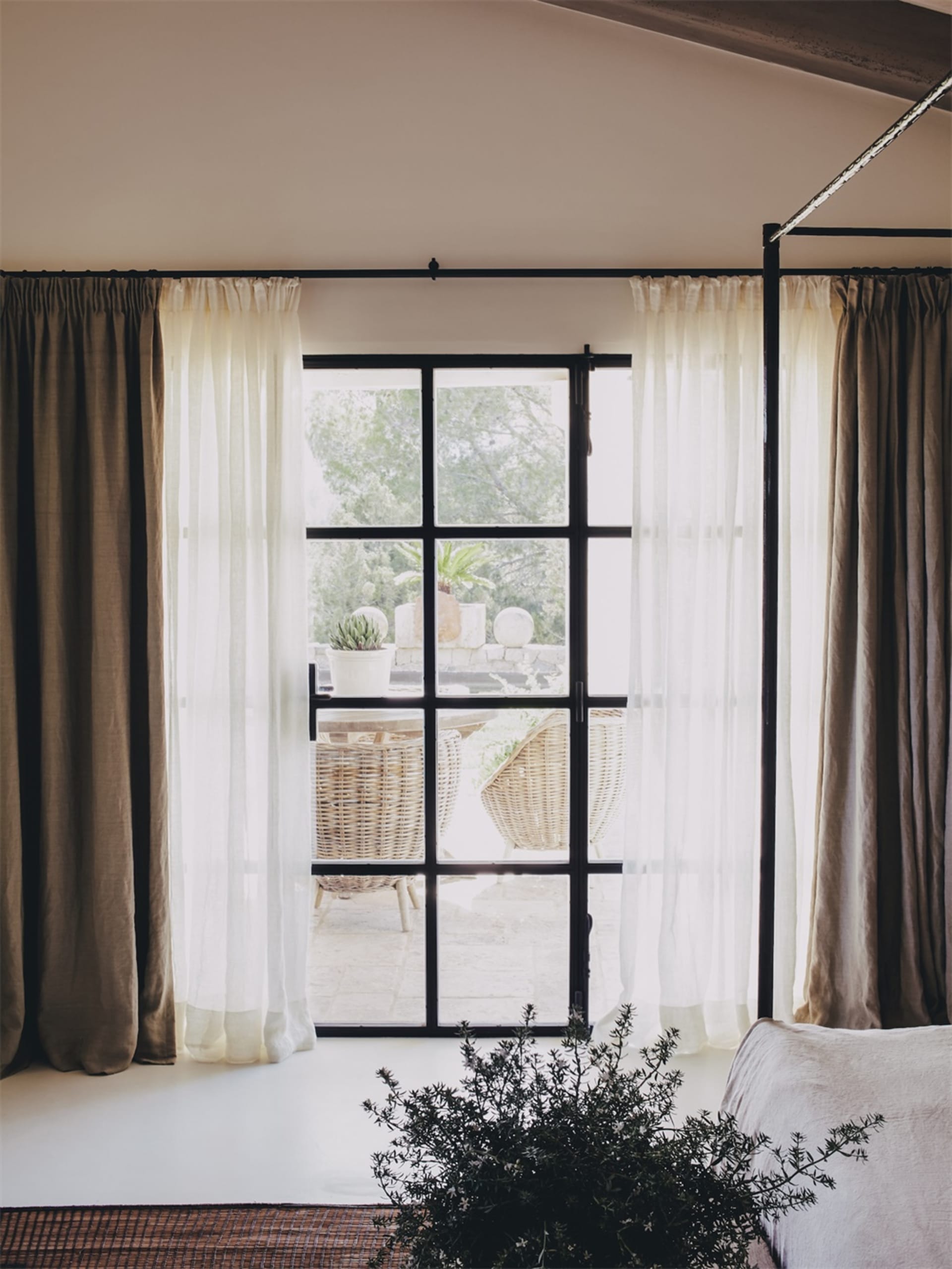 A window with transparent curtains next to a plant.