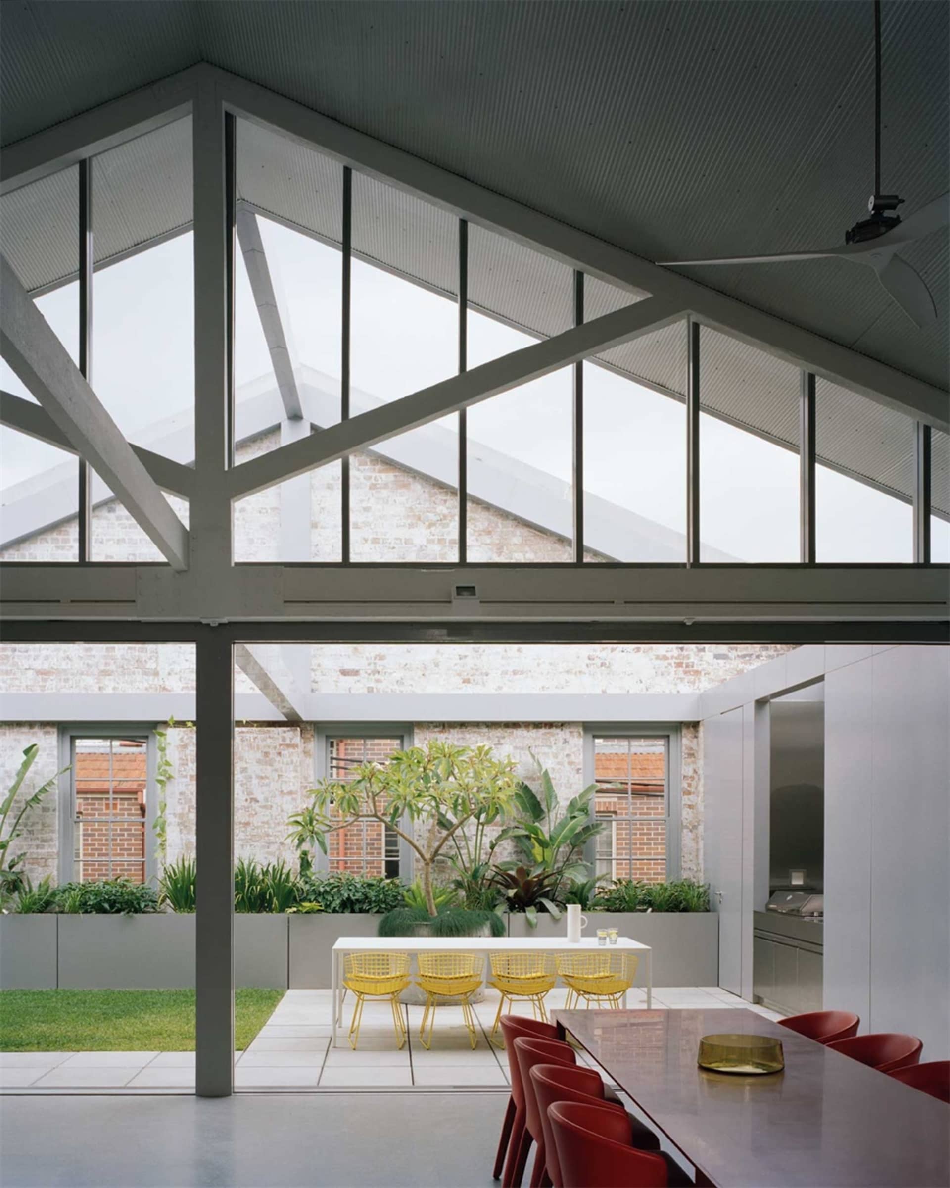 A minimalist living space with concrete walls, floor-to-ceiling windows, and indoor plants.