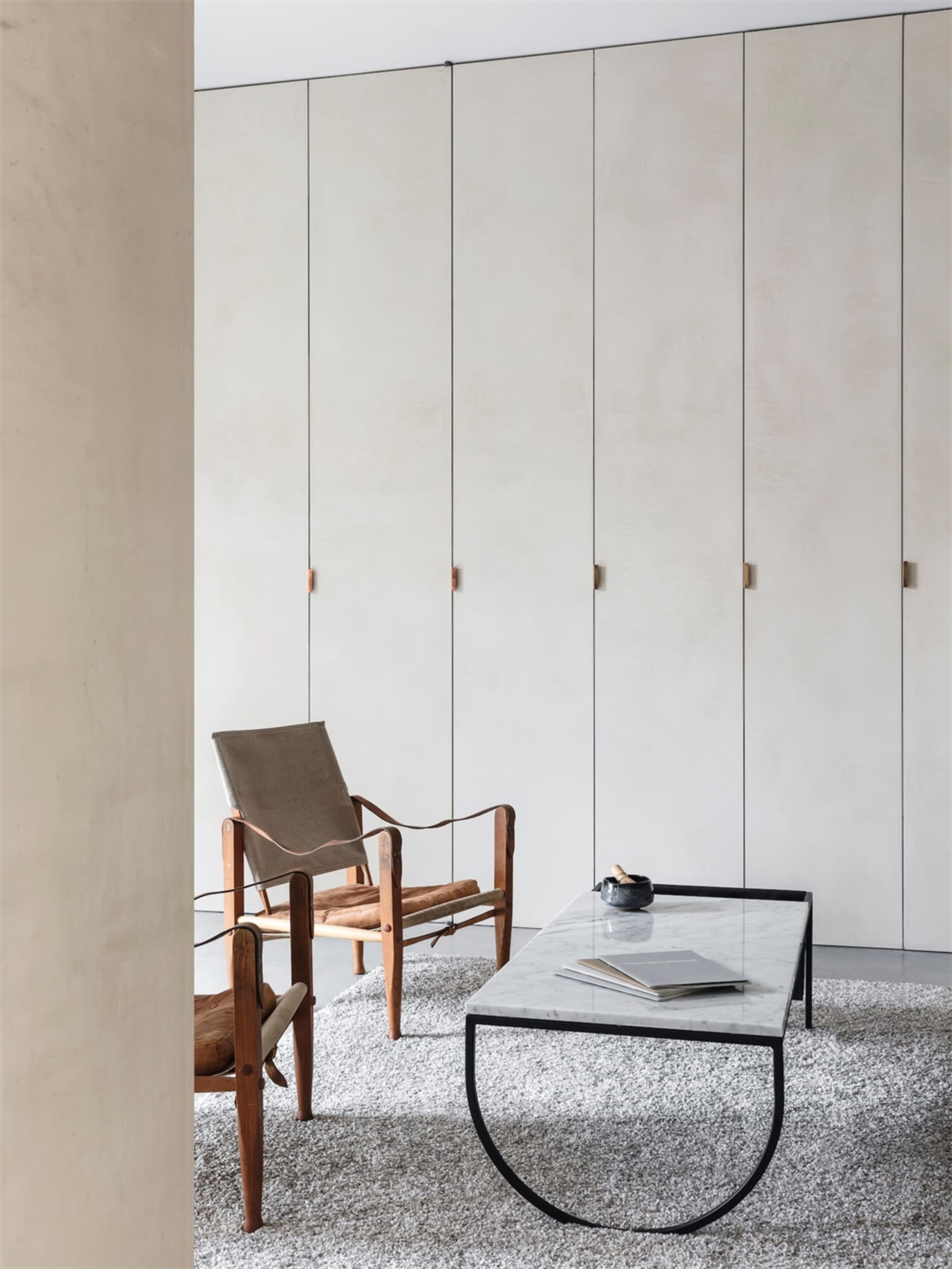 Modern minimalist living room featuring wood, leather, and marble accents.