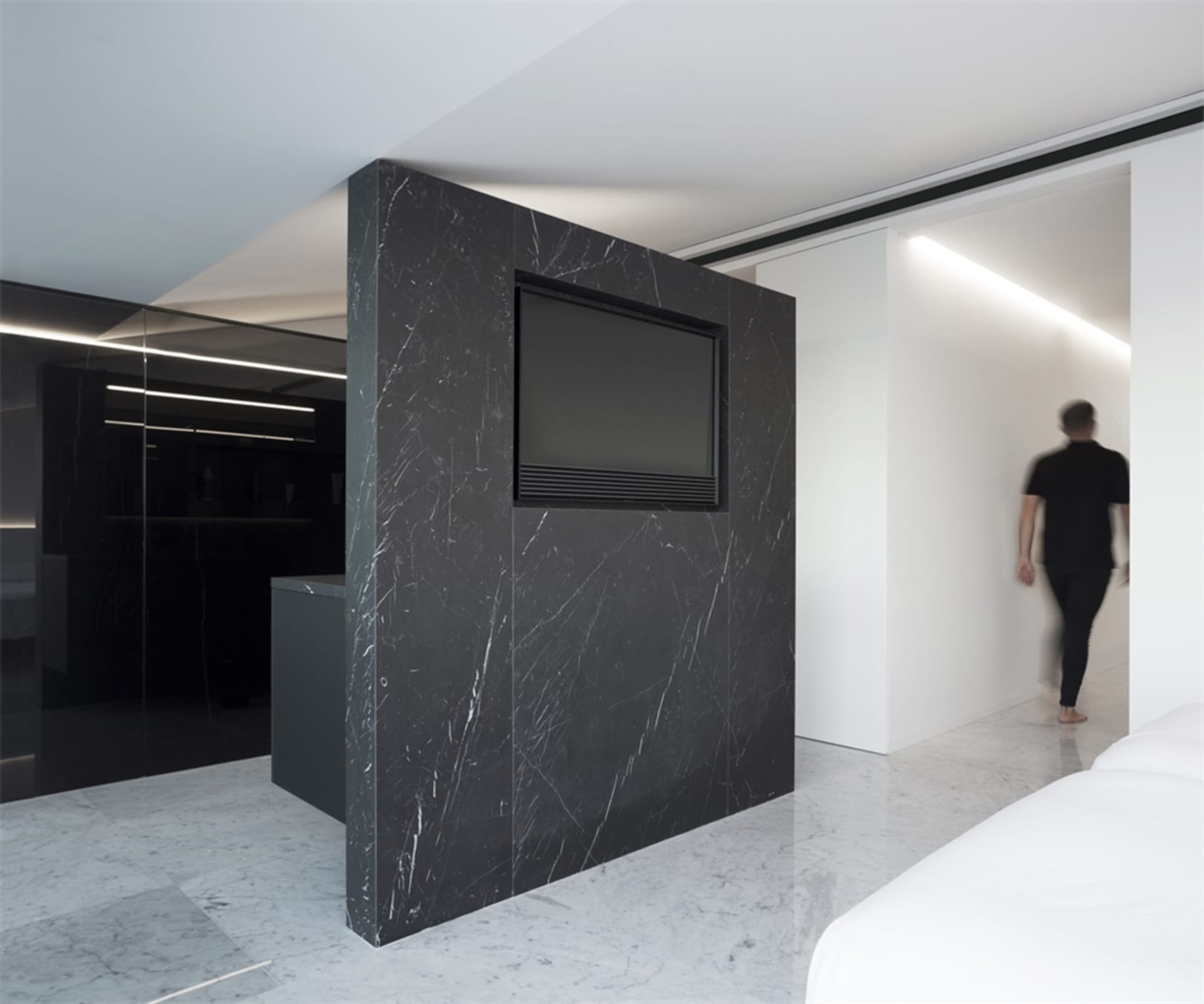 A modern kitchen with a black marble backsplash and black marble countertops, featuring a black television mounted on the wal