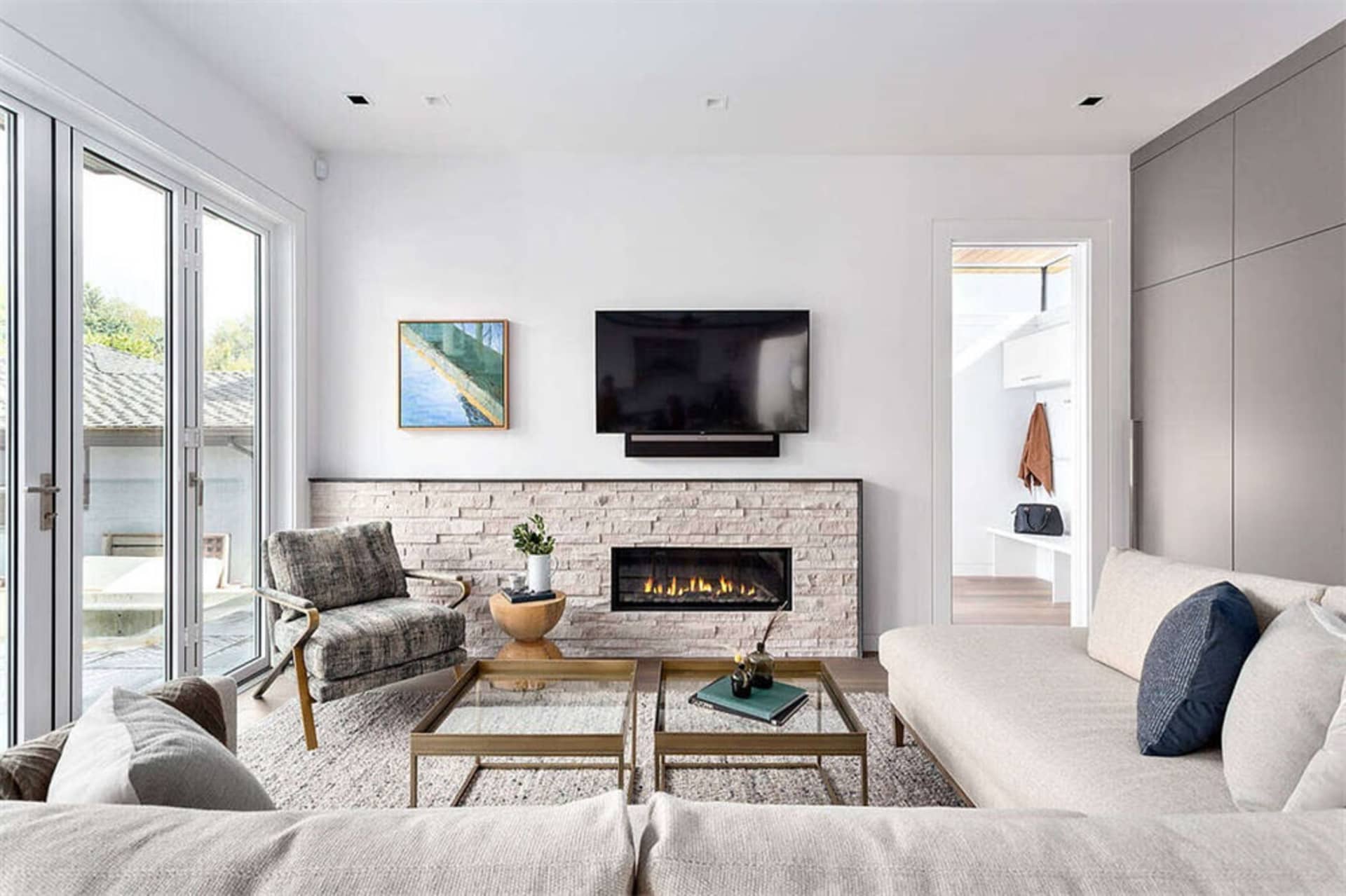 Modern living room featuring a comfortable seating area, a cozy fireplace, and a flat-screen TV on a white wall.