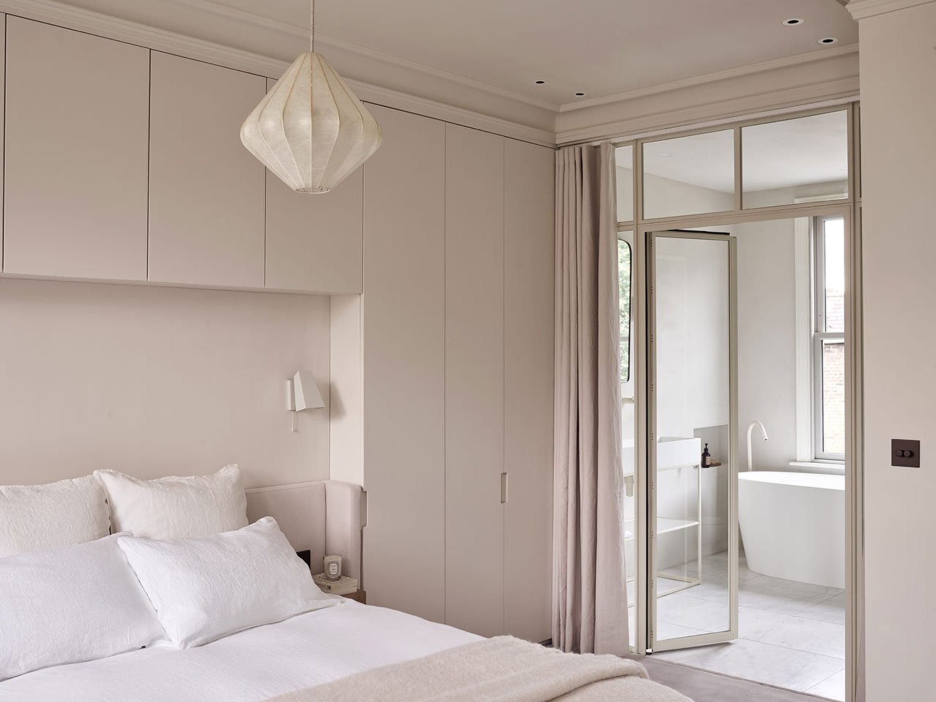 A minimalist bedroom with soft, neutral-colored decor and a clean, organized layout.