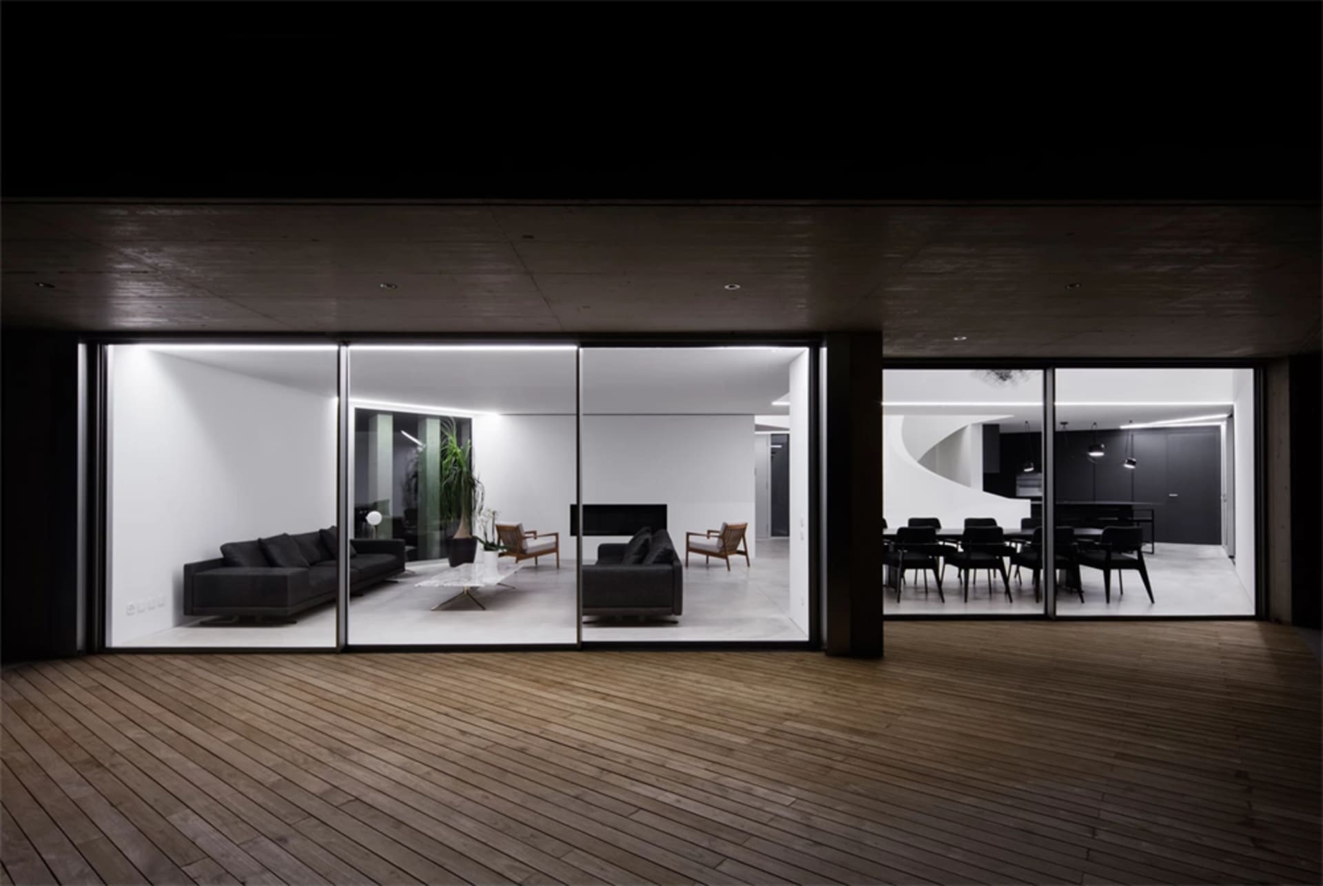 Modern living room with concrete walls and floor, featuring a cozy seating area and a minimalist design.