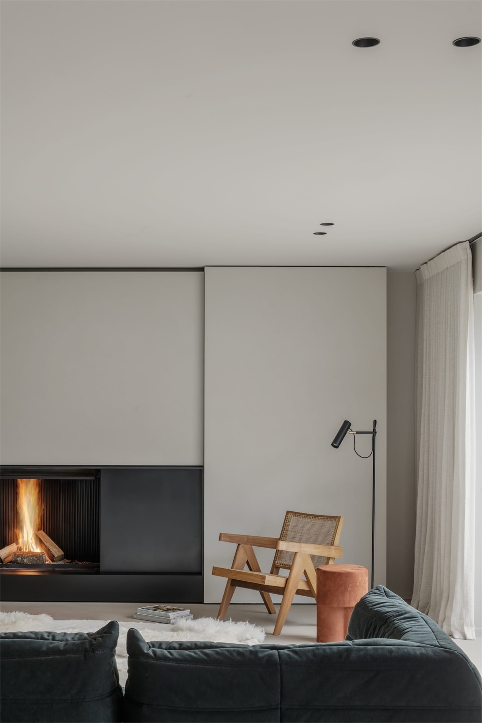 A modern living room with dark oak wood flooring, a leather couch, and a glass wall.