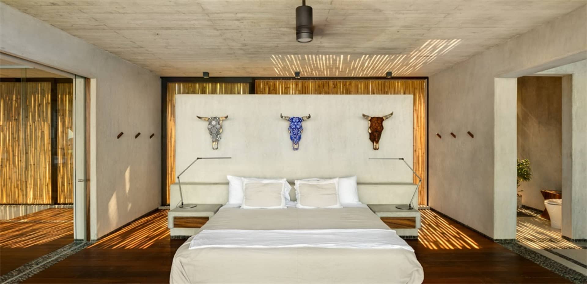 Bedroom with modern minimalist design, featuring concrete headboard and wood floor.