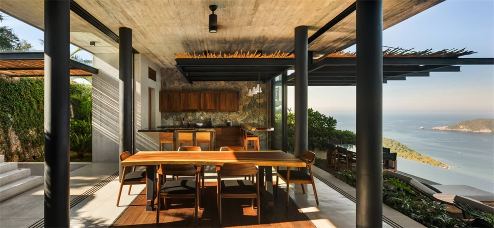 Modern patio area with wooden furniture overlooking the ocean.
