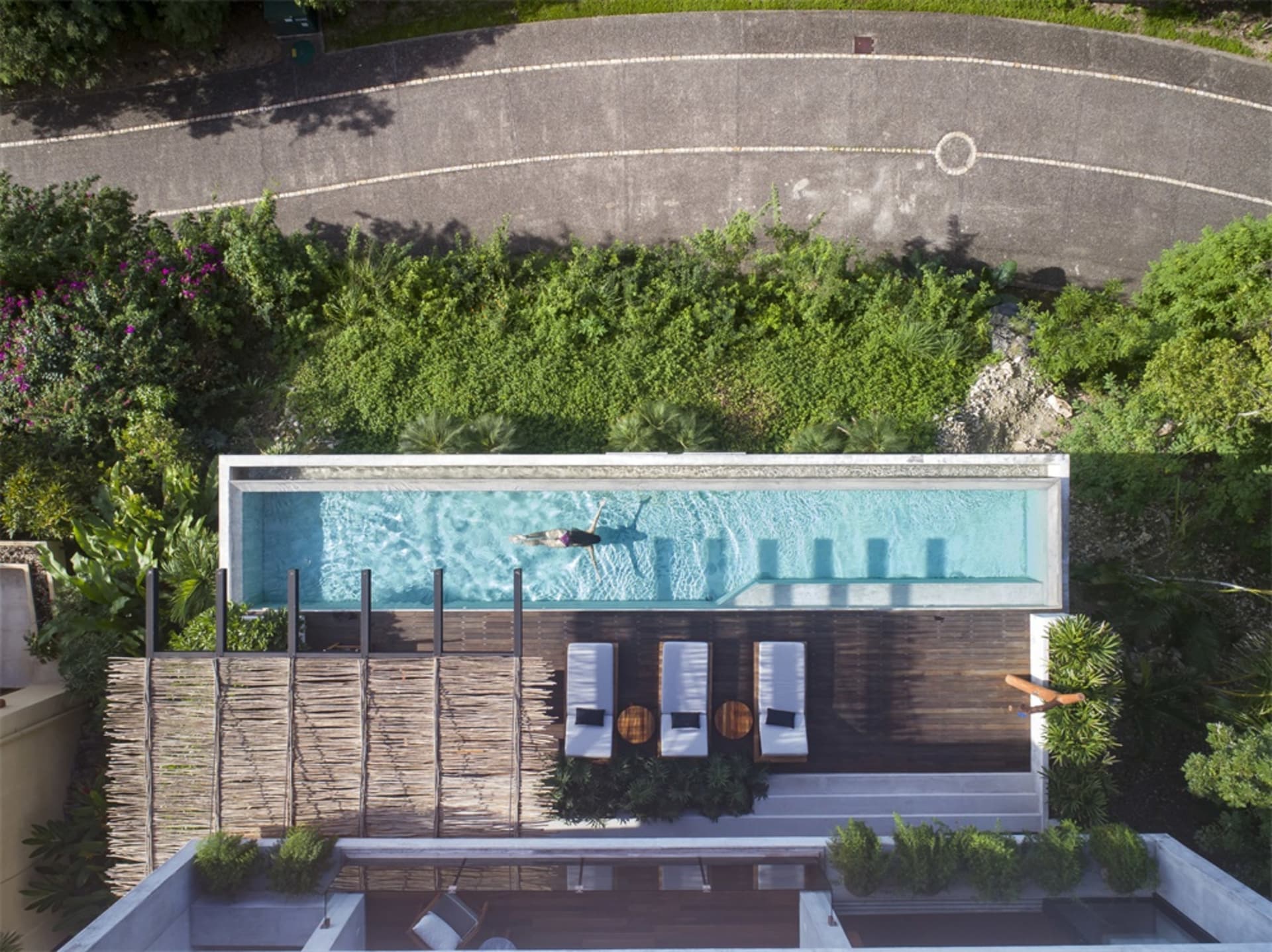 A modern swimming pool with concrete walls and adjacent lounge chairs.