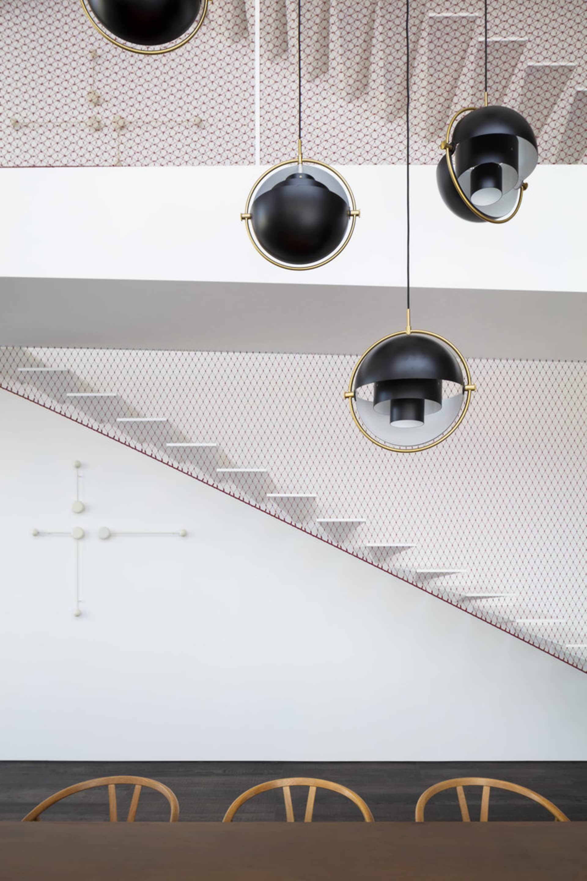 A modern dining room with contemporary lighting fixtures and a geometric staircase.
