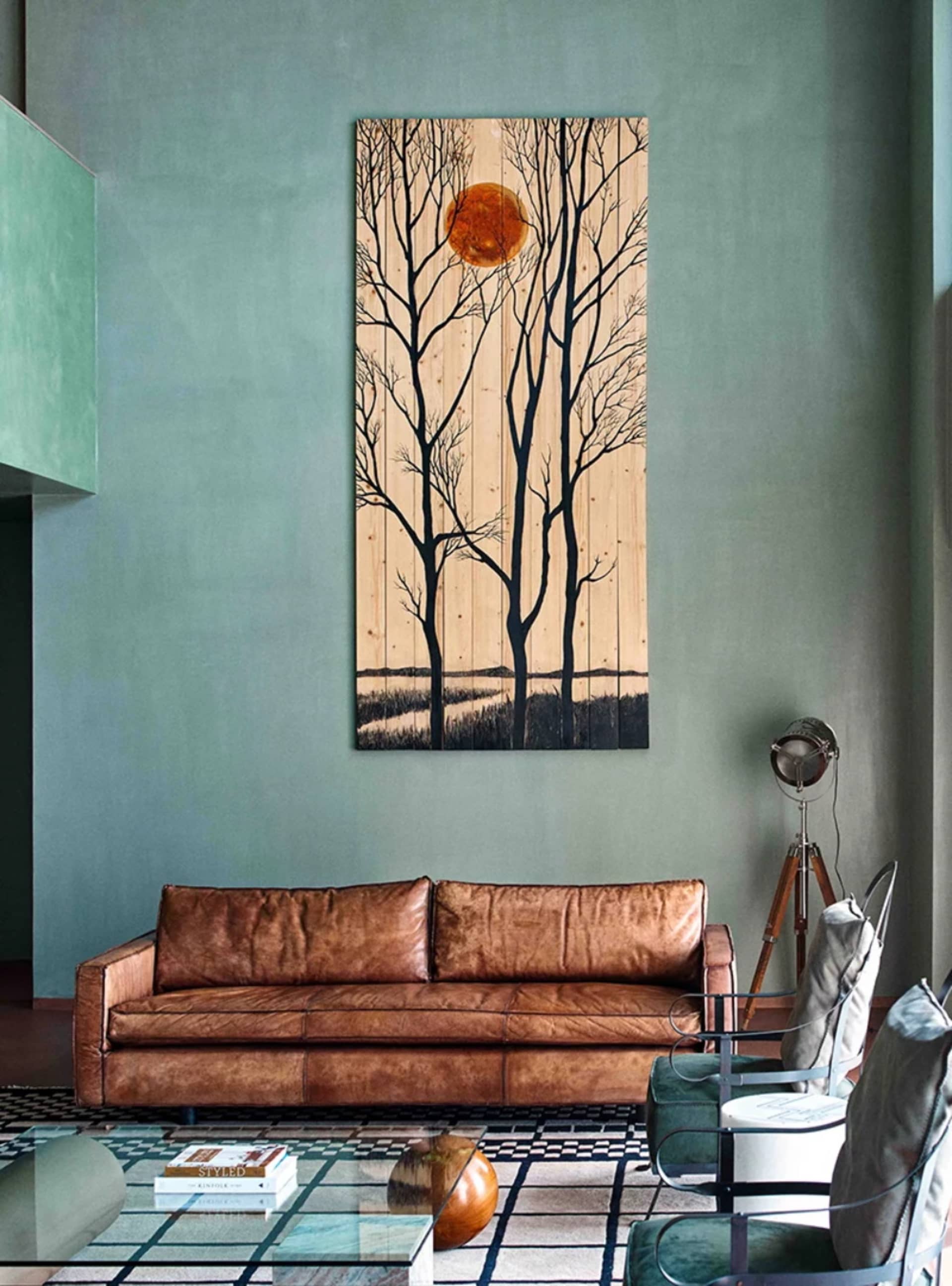 A modern living room featuring a wooden artwork with sun and trees displayed on the wall.