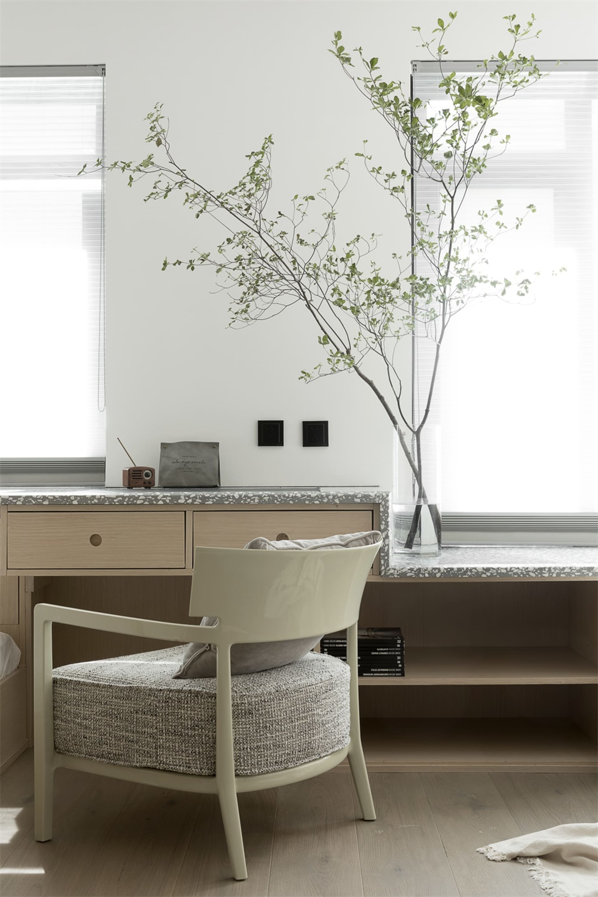 A modern home office featuring a wooden chair with a textured seat, a wooden desk with a terrazzo countertop, and a terrazzo 