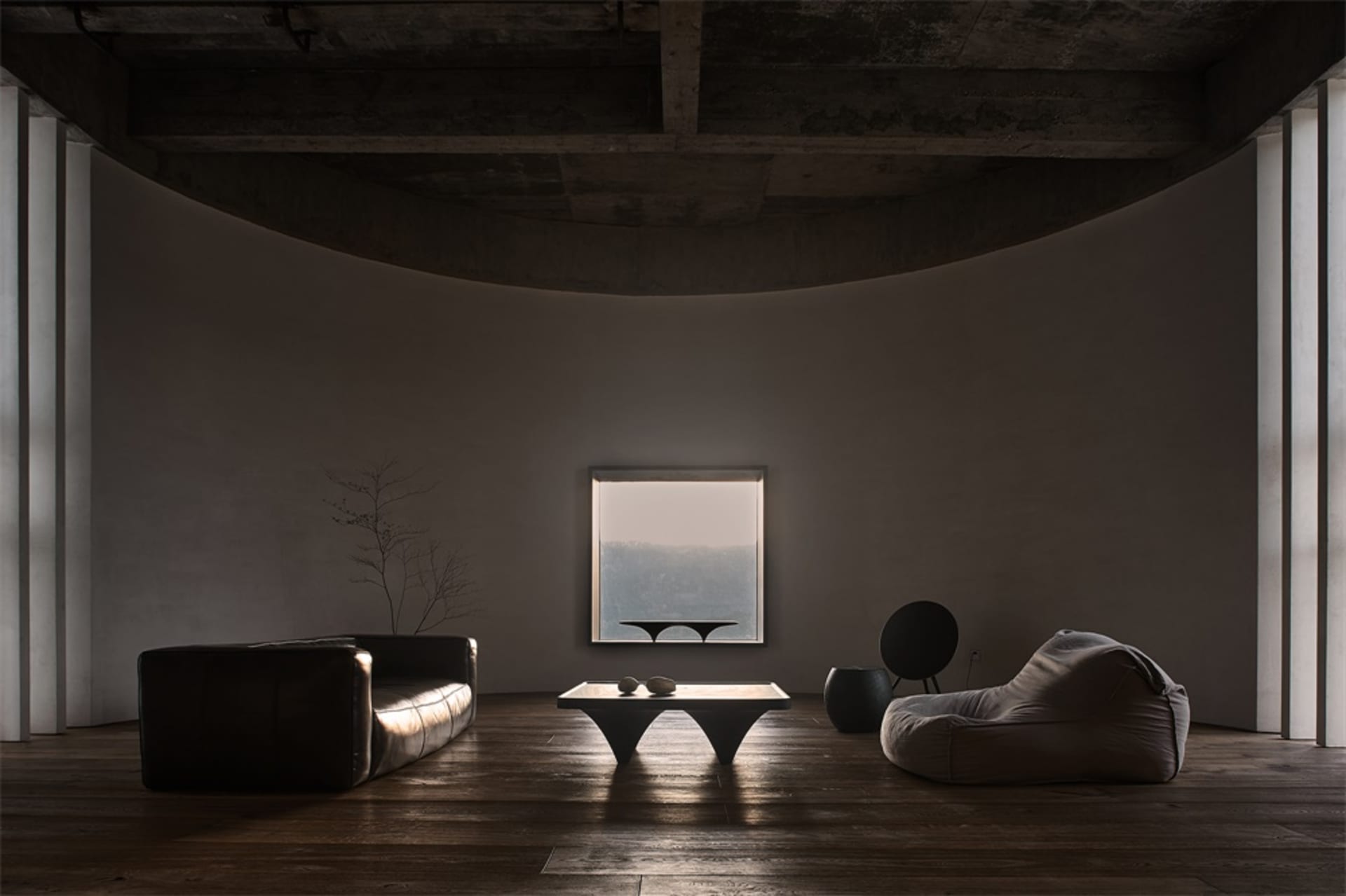 A minimalist living room with concrete furniture and a large window overlooking a serene landscape.