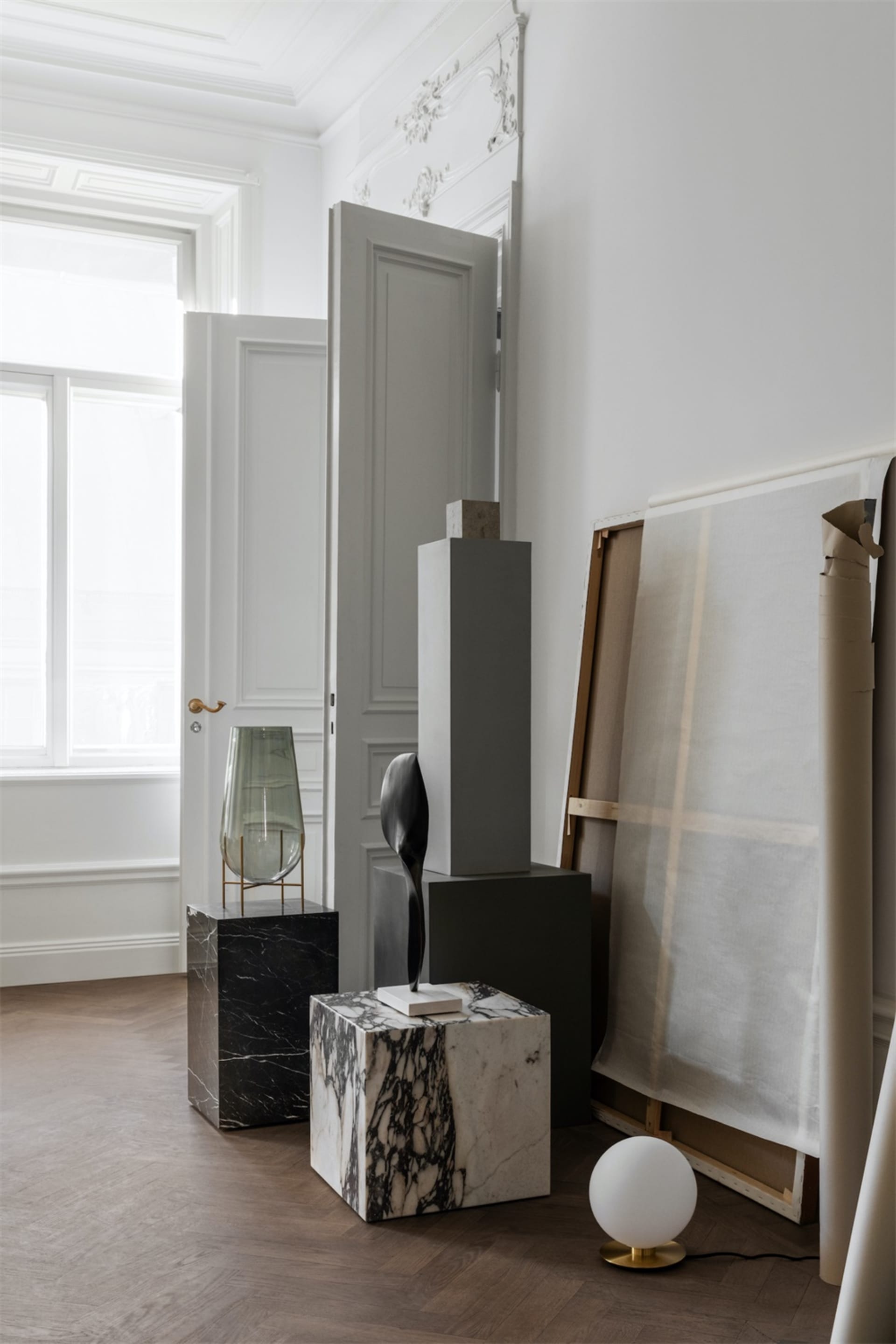 Modern interior with sculptures displayed on marble pedestals against a white wall.