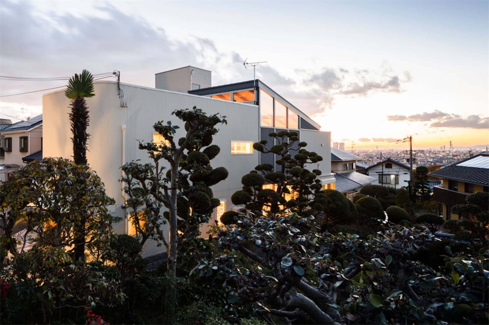 A modern residential house with metallic exterior, glass windows, and concrete accents.