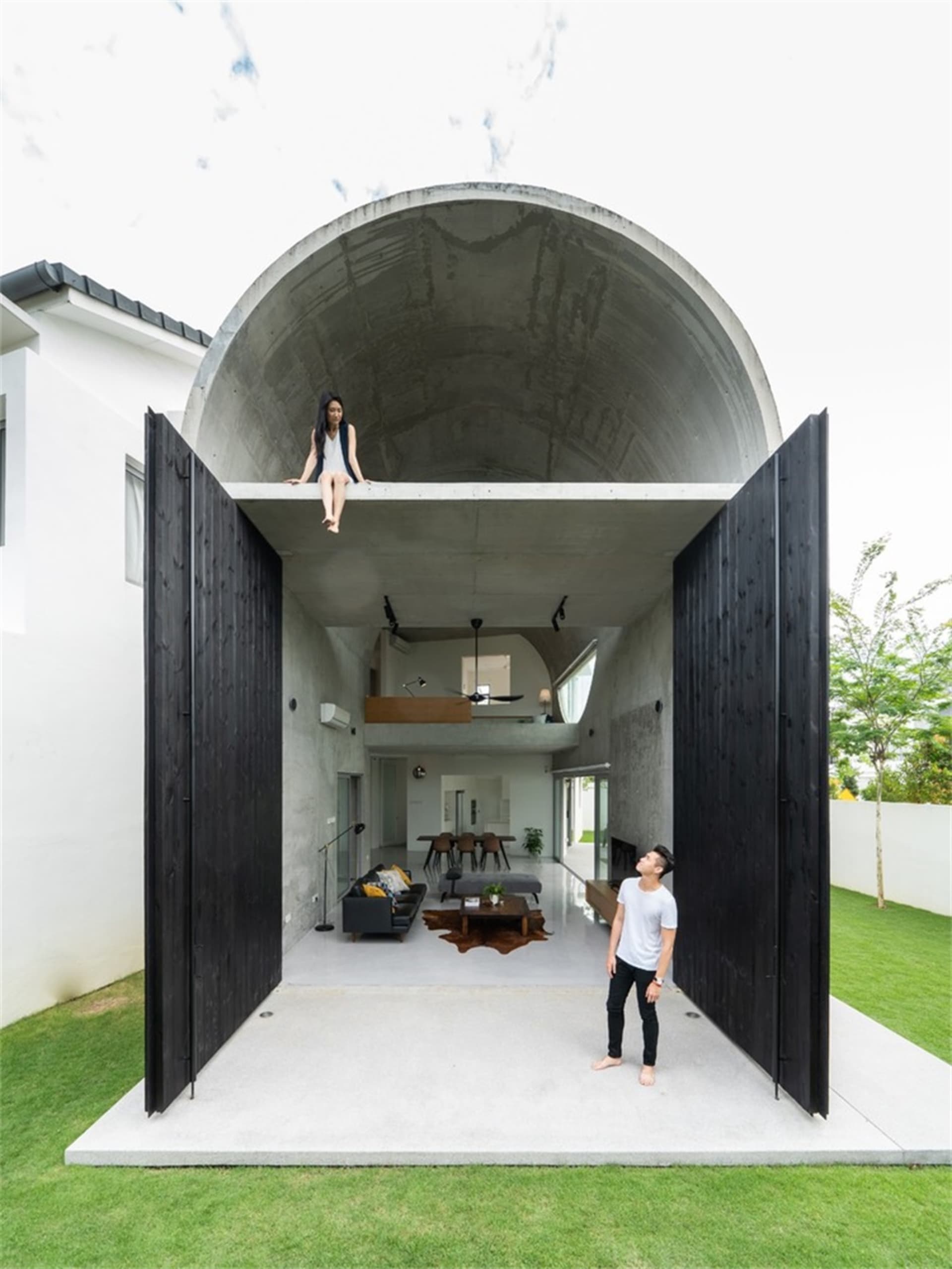 A minimalist house with a concrete tunnel structure, featuring a spacious interior with large windows and a sleek, modern des