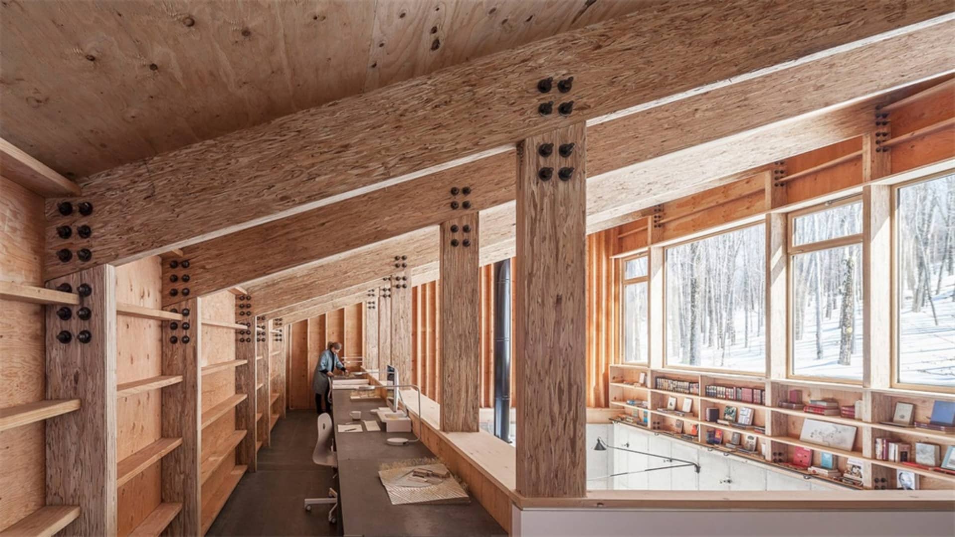 A spacious industrial-style library with wooden shelves and beams.