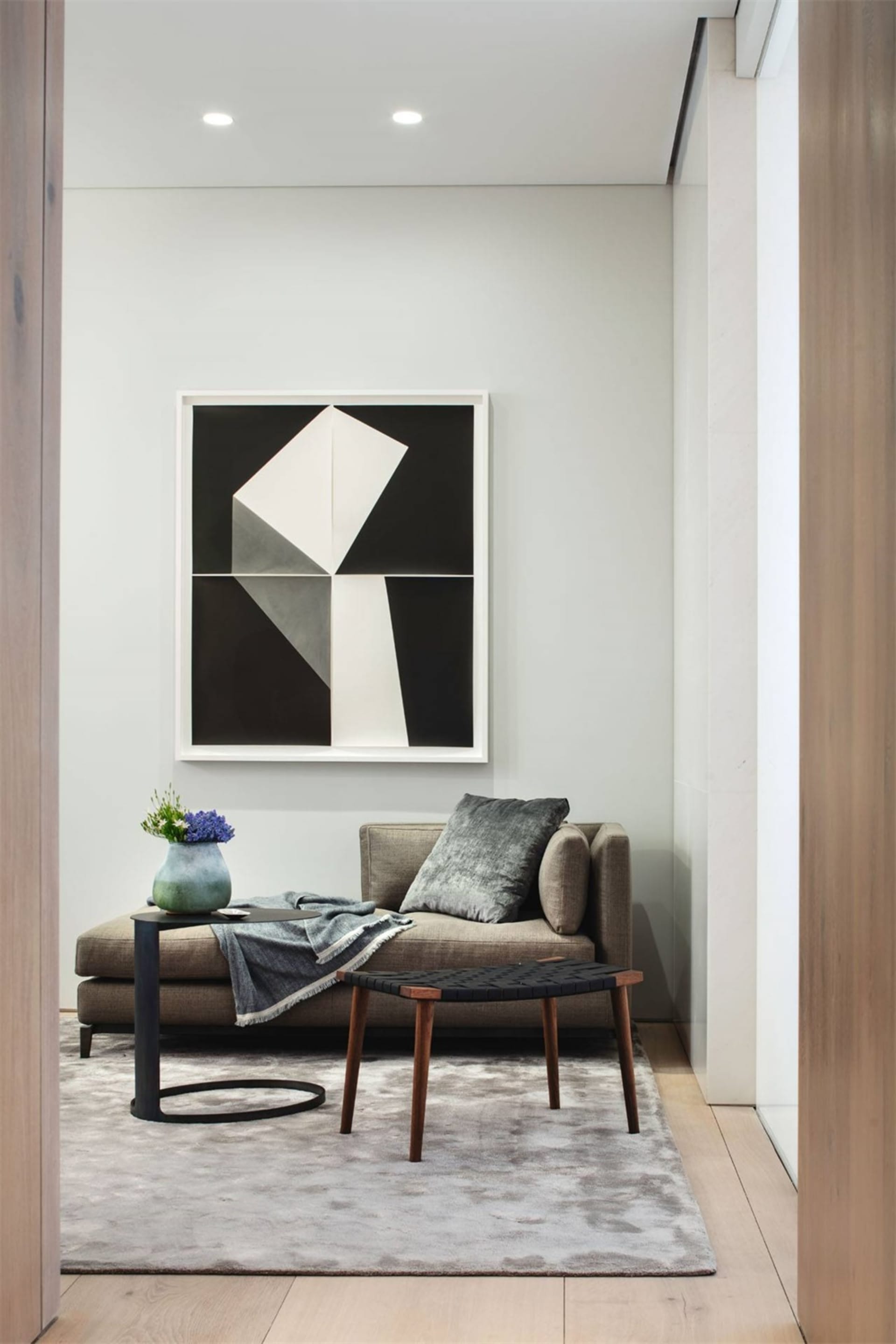 A minimalist living room with a gray sofa, geometric artwork, and modern side table.