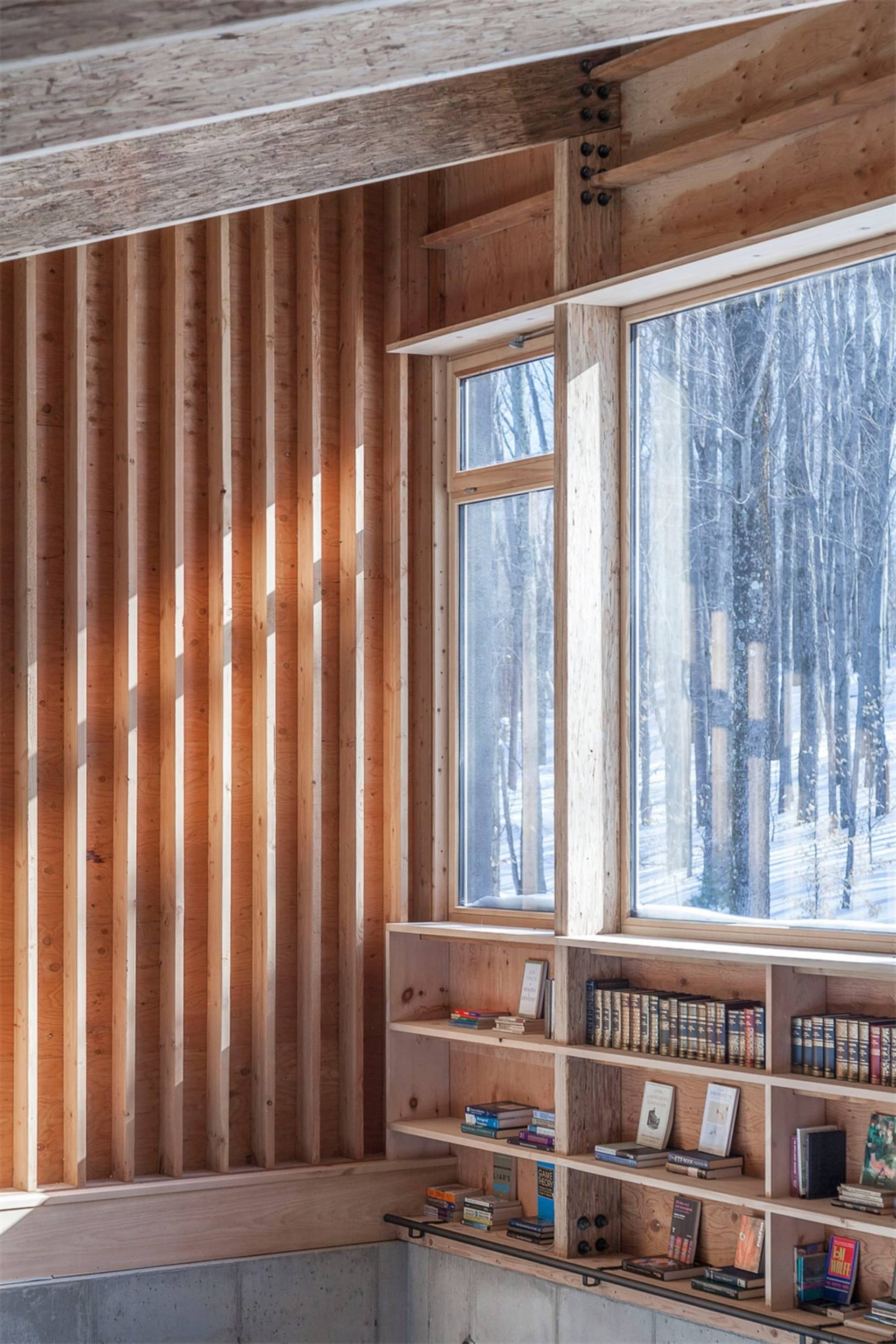 A modern bookshelf with wooden shelves next to a large window.